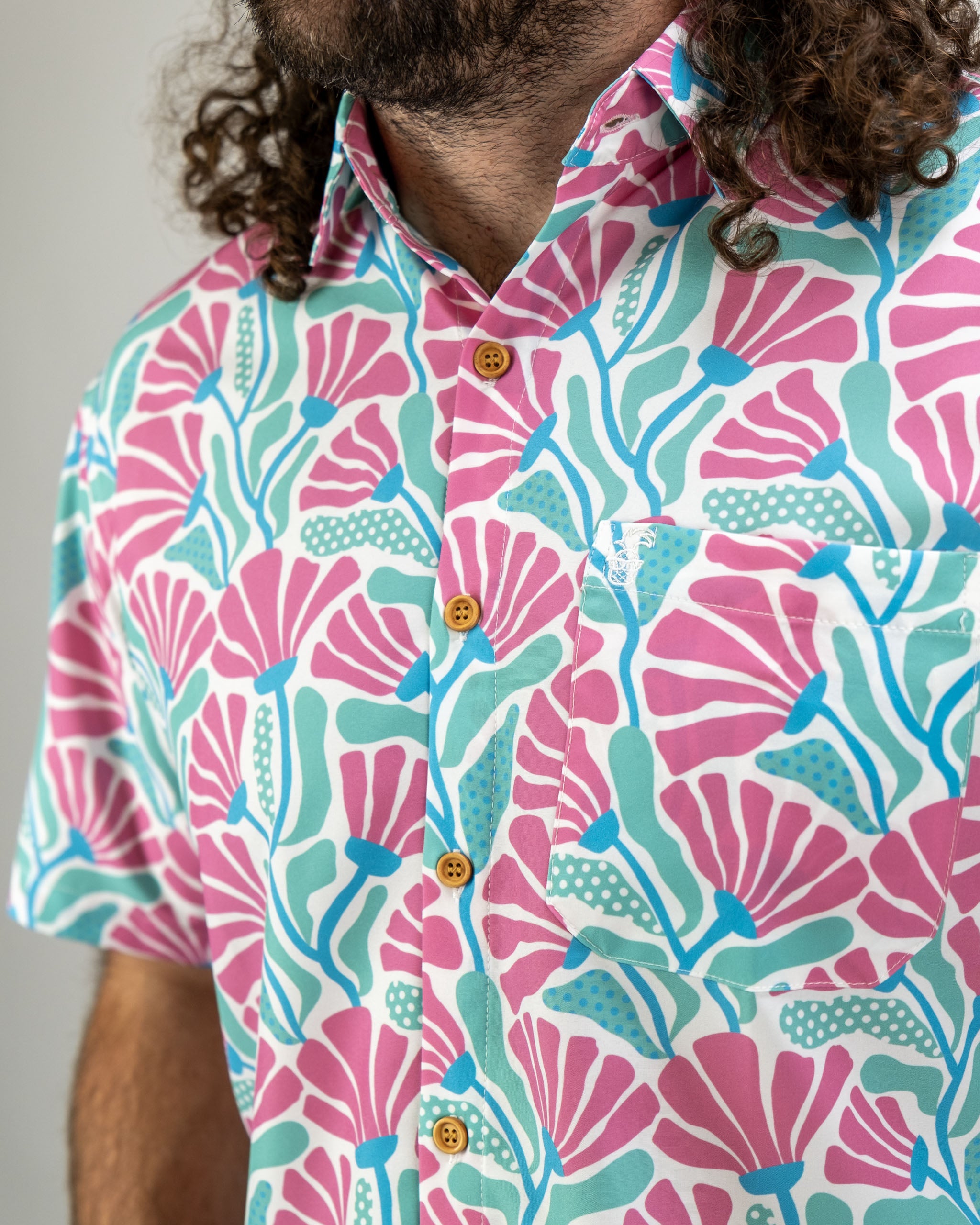 Men's short-sleeve shirt featuring a vibrant coral and teal floral pattern, perfect for stylish golf outings.