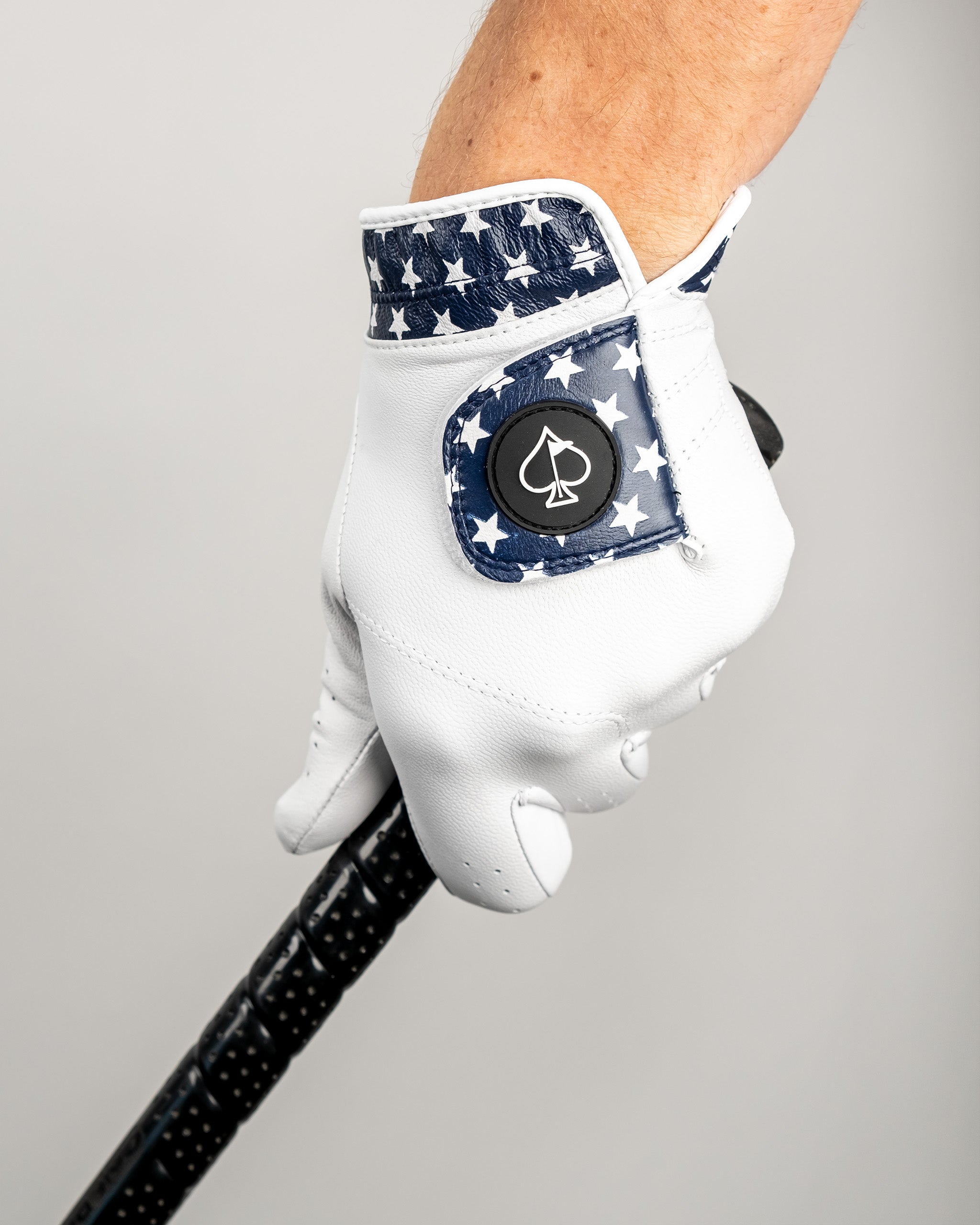 White golf glove with a star-spangled navy cuff and a black logo button, designed for bold, standout golf style.