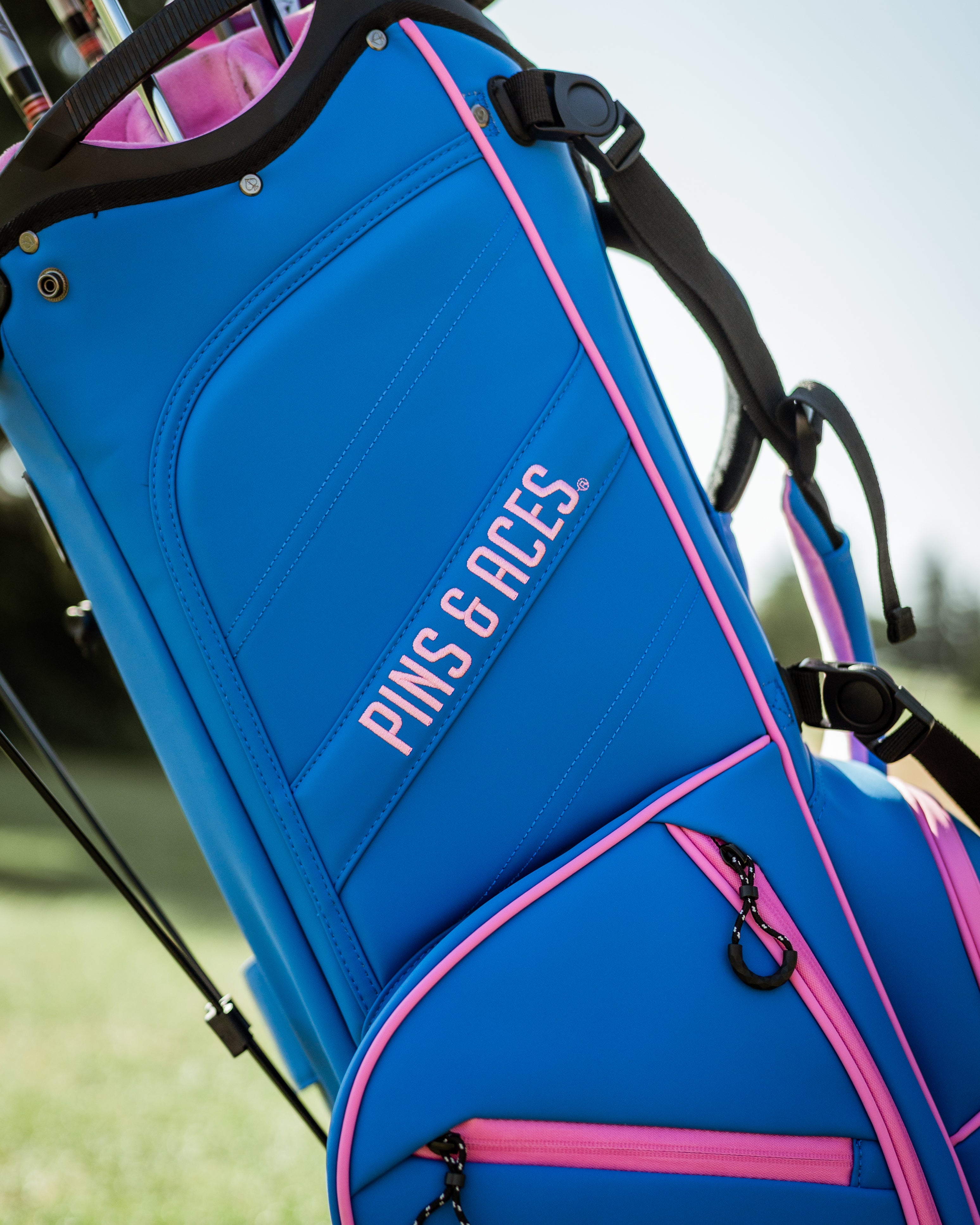 Bold blue raspberry golf bag with pink accents, featuring the Pins & Aces logo, designed for stylish golfers.