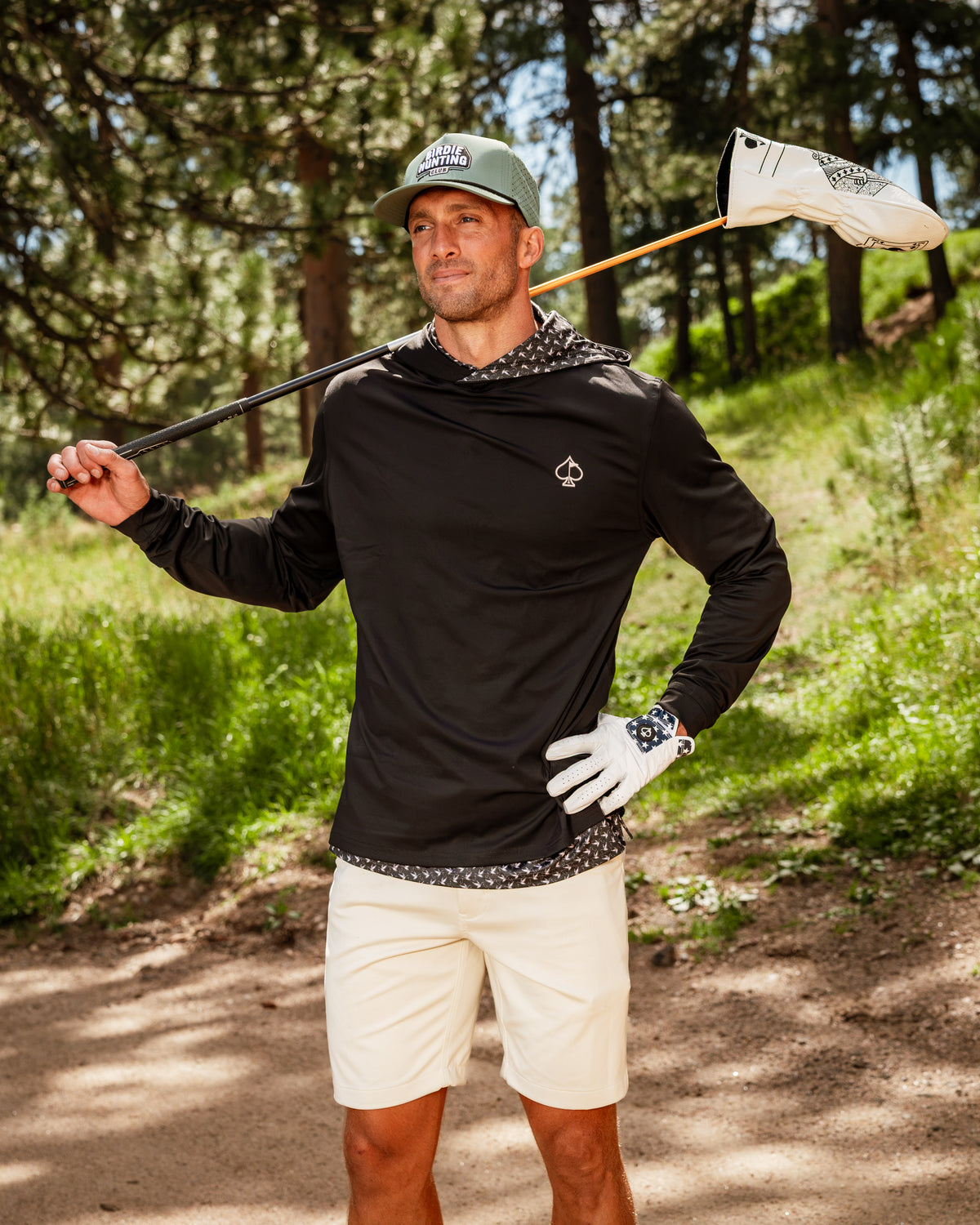 Performance Golf Hoodie in black with a unique duck hook design, worn by a golfer in a natural outdoor setting.
