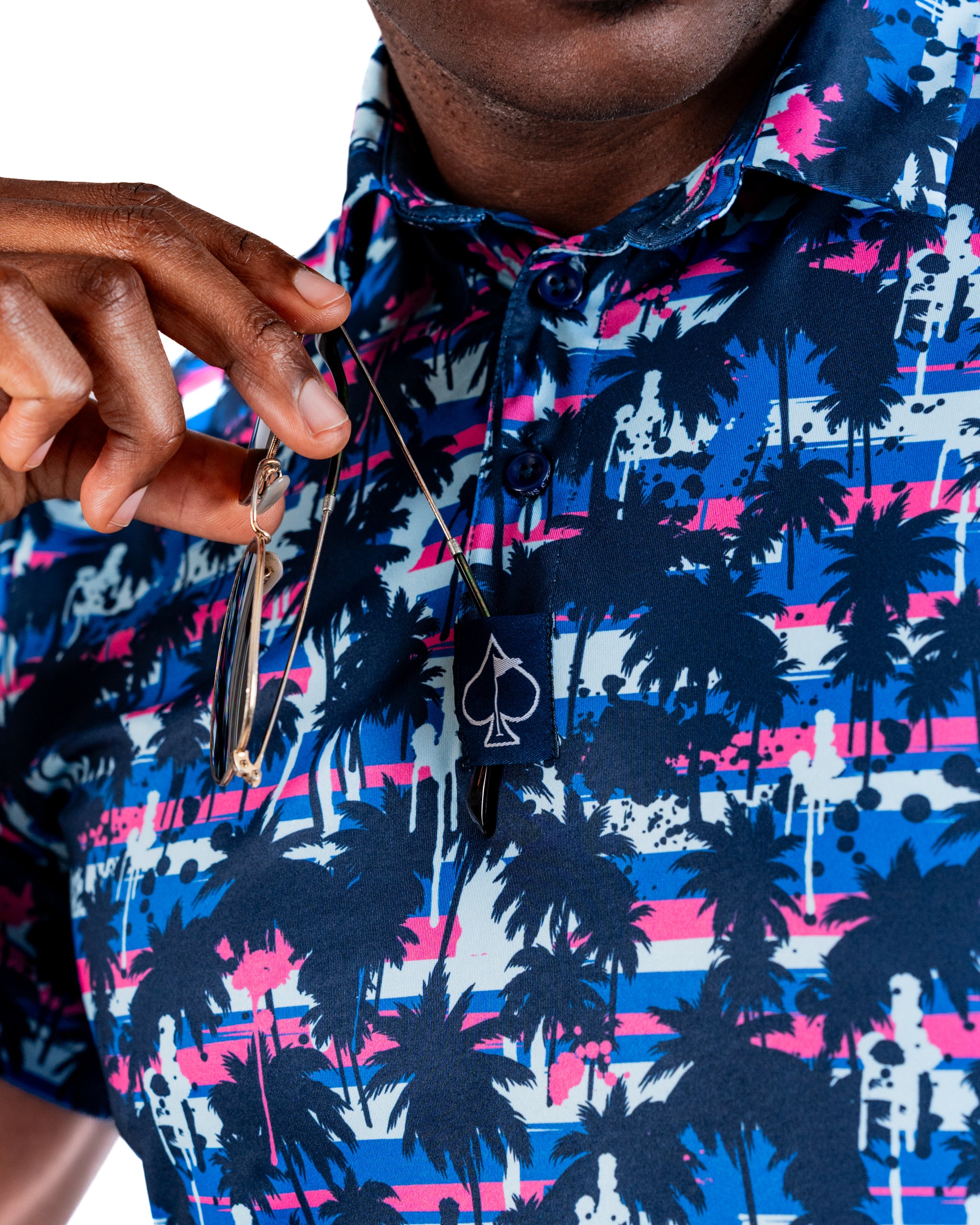 Bold golf polo featuring a vibrant palm tree and sunset design in blue, pink, and white, perfect for stylish golfers.
