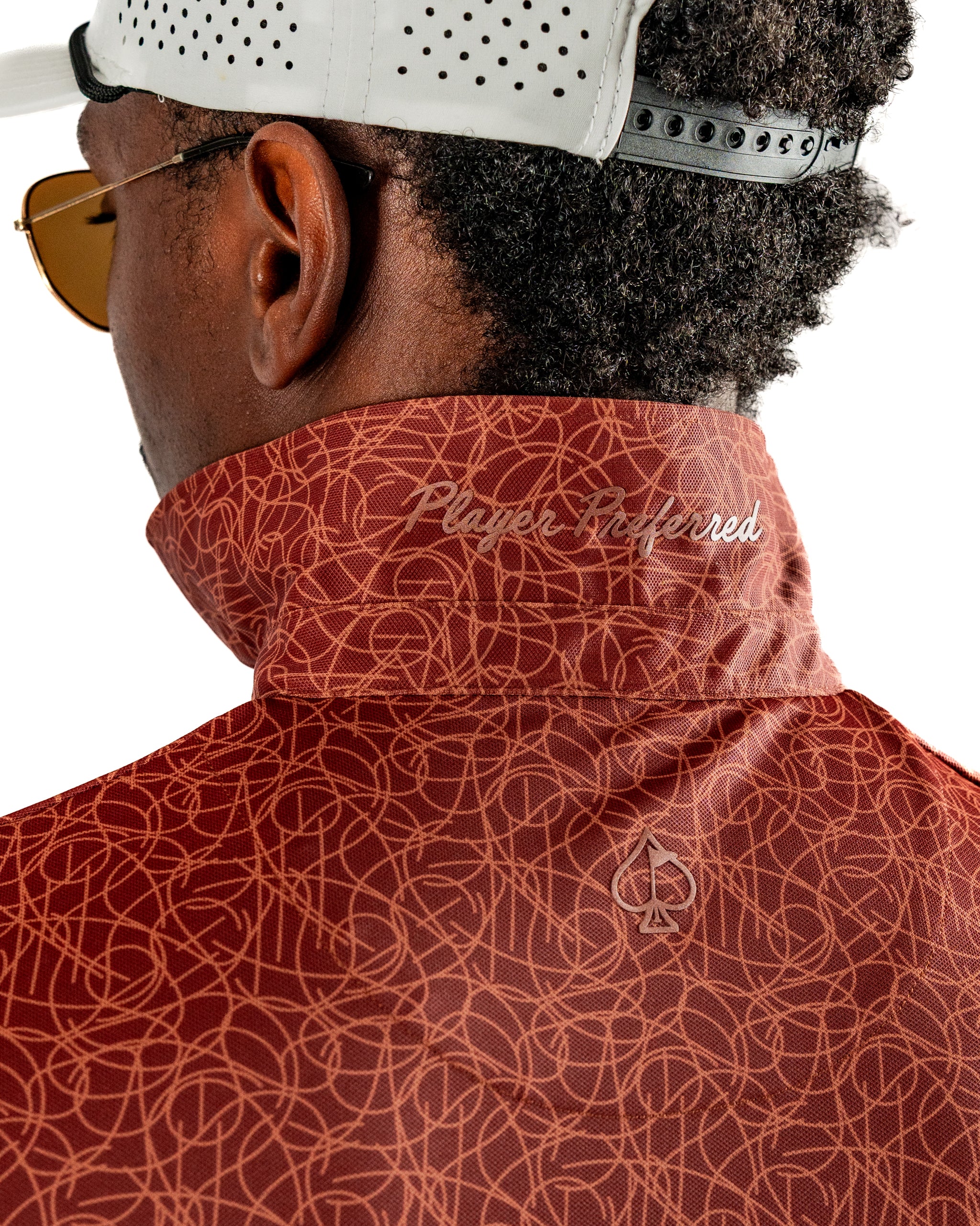 Stylish golfer wearing a patterned red Filament jacket with a high collar and "Player Preferred" embroidery on the back.