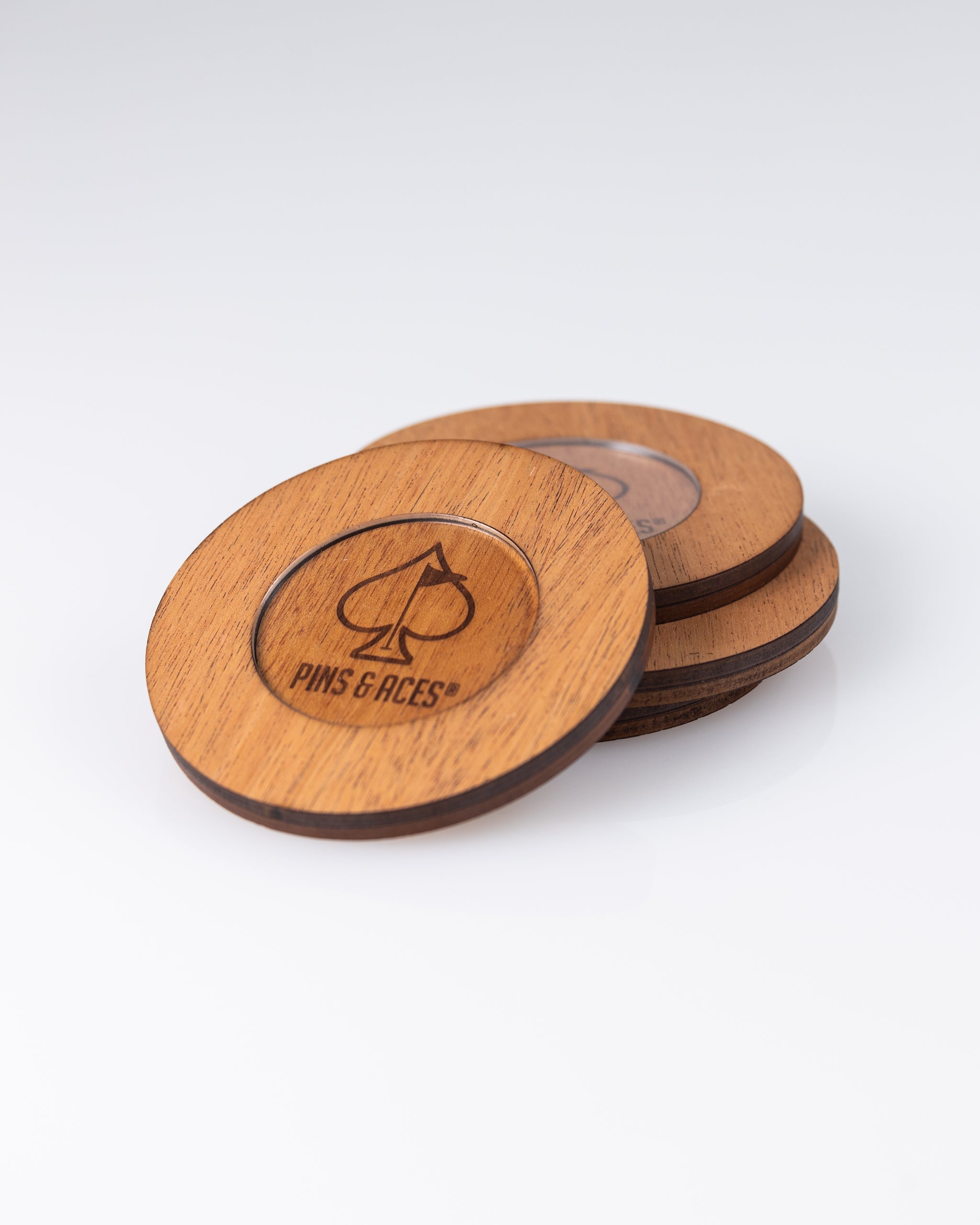Wooden golf ball markers with "Pins & Aces" logo and spade symbol, featuring a natural wood finish and dark engraved details.