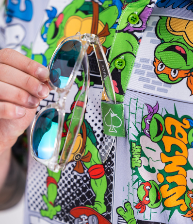 Colorful TMNT comic strip golf shirt featuring vibrant characters and graphics, with sunglasses hanging from the collar.