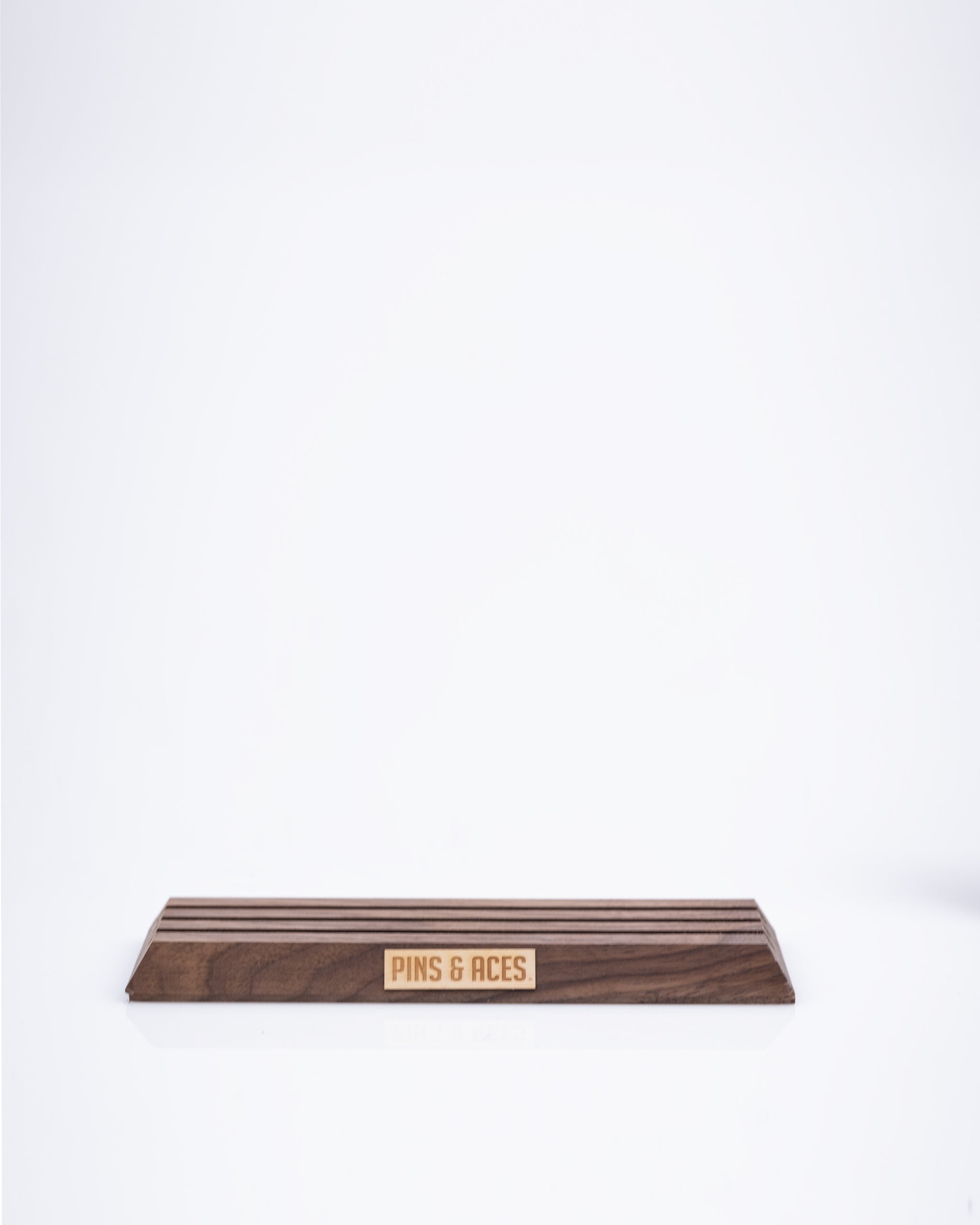 Wooden ball marker display stand featuring a sleek design and engraved Pins and Aces logo, ideal for showcasing golf markers.