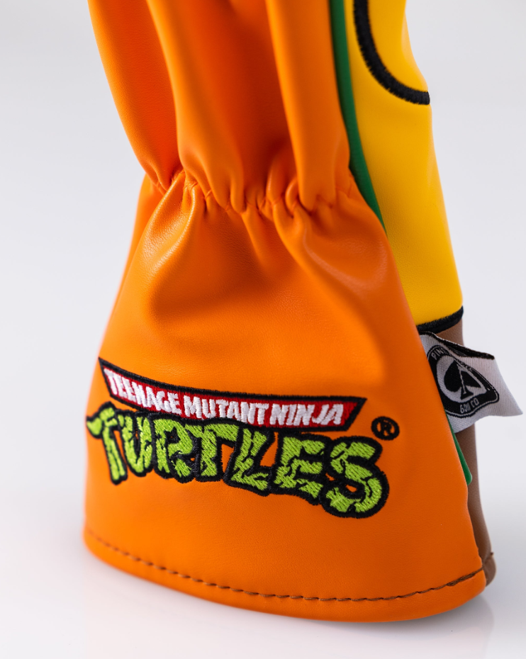 Michelangelo hybrid golf club cover featuring vibrant orange and yellow design with Teenage Mutant Ninja Turtles logo.