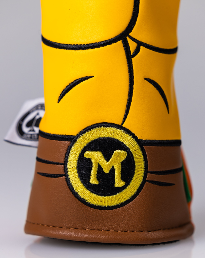 Close-up of a Michelangelo hybrid golf headcover featuring a vibrant yellow design and a prominent "M" logo.