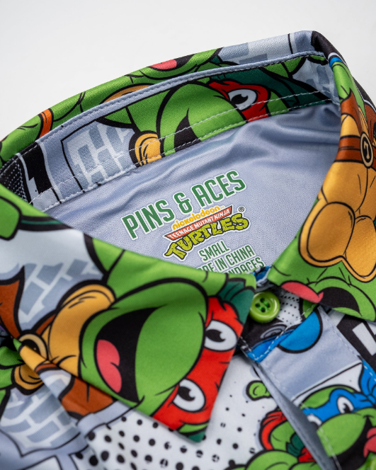 Youth shirt featuring a vibrant TMNT comic strip design with colorful characters and a playful collar.