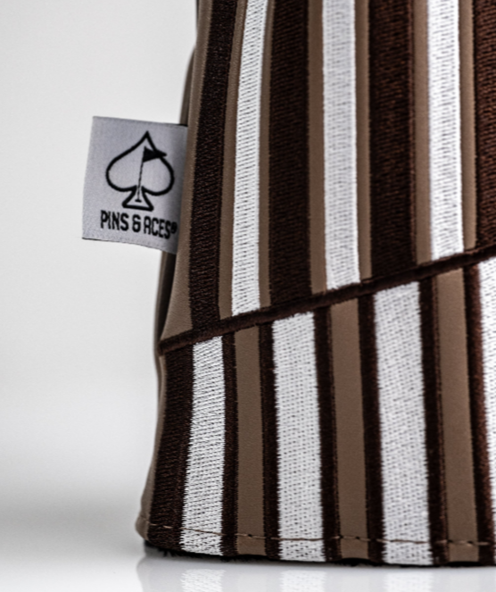 Brown and white striped driver cover featuring a Pins and Aces logo, designed for stylish golf enthusiasts.