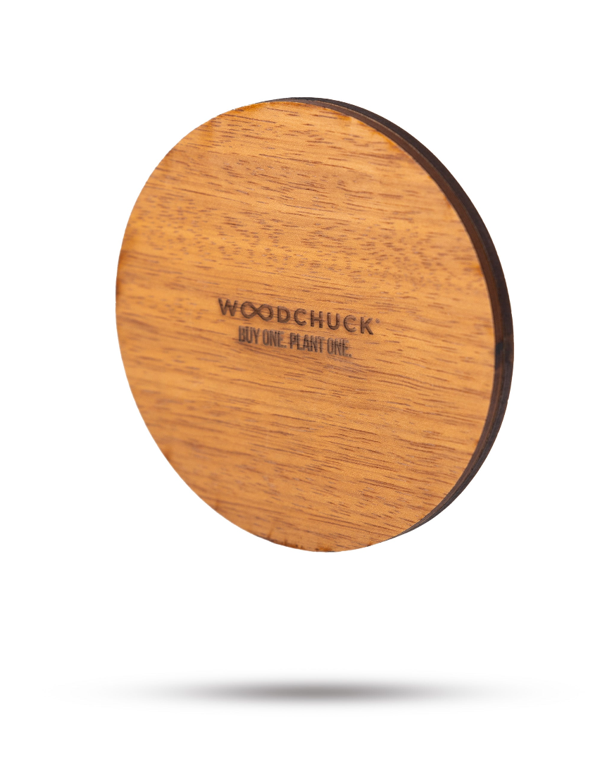 Natural wood coaster featuring the engraved logo "WOODCHUCK" with the phrase "BUY ONE. PLANT ONE." for eco-friendly appeal.