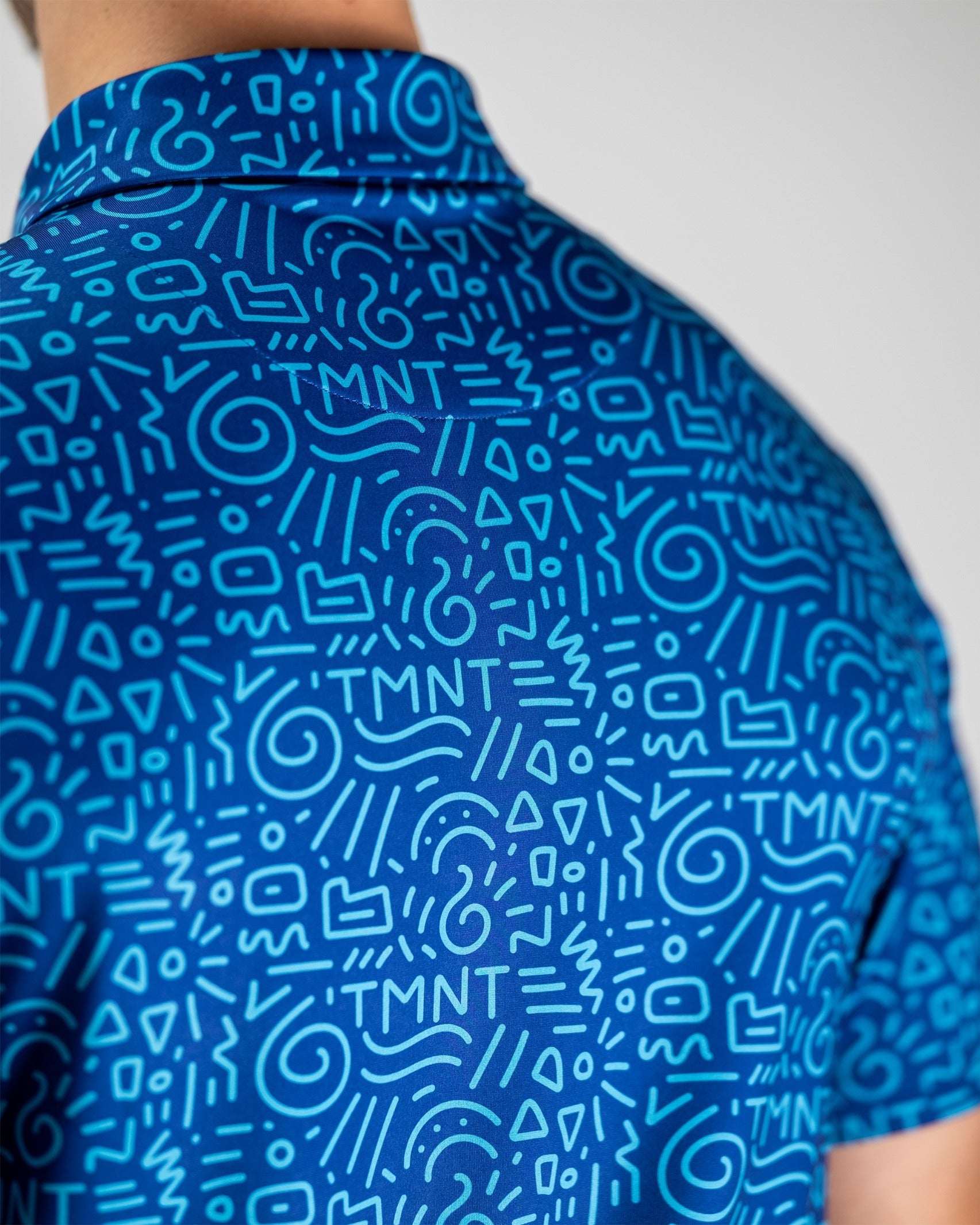 Bold blue golf shirt featuring a playful doodle pattern with TMNT graphics, perfect for fans wanting to stand out on the course.