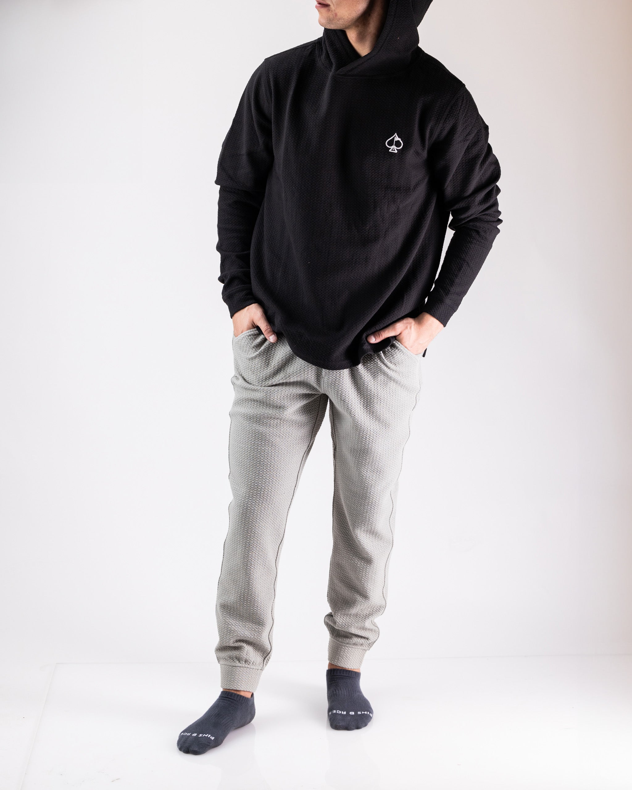 Stylish man wearing a black hoodie and slate-colored waffleknit joggers, showcasing a relaxed, sporty look.