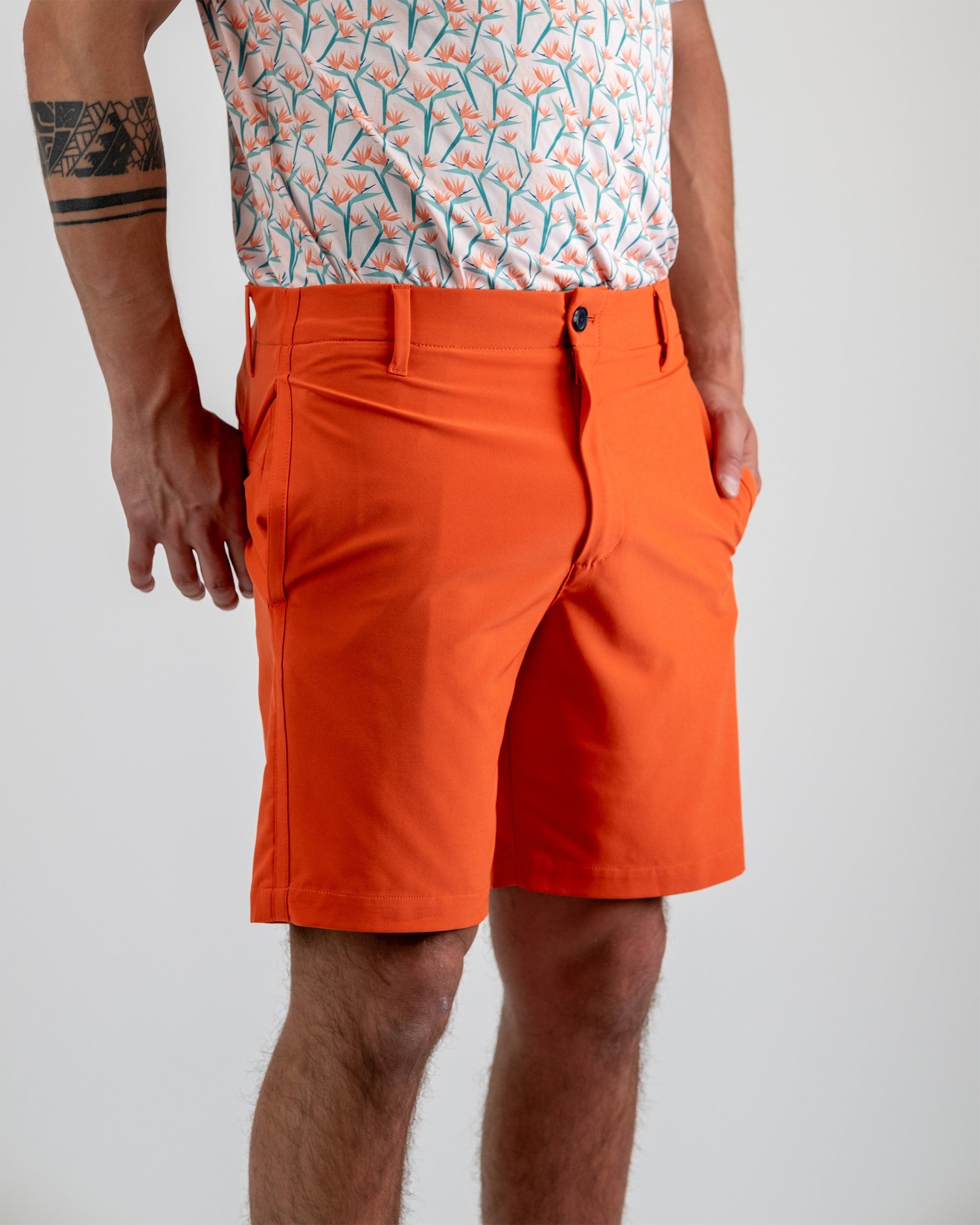Men's performance shorts in vibrant melon color, featuring a tailored fit and side pockets, perfect for golf and outdoor activities.
