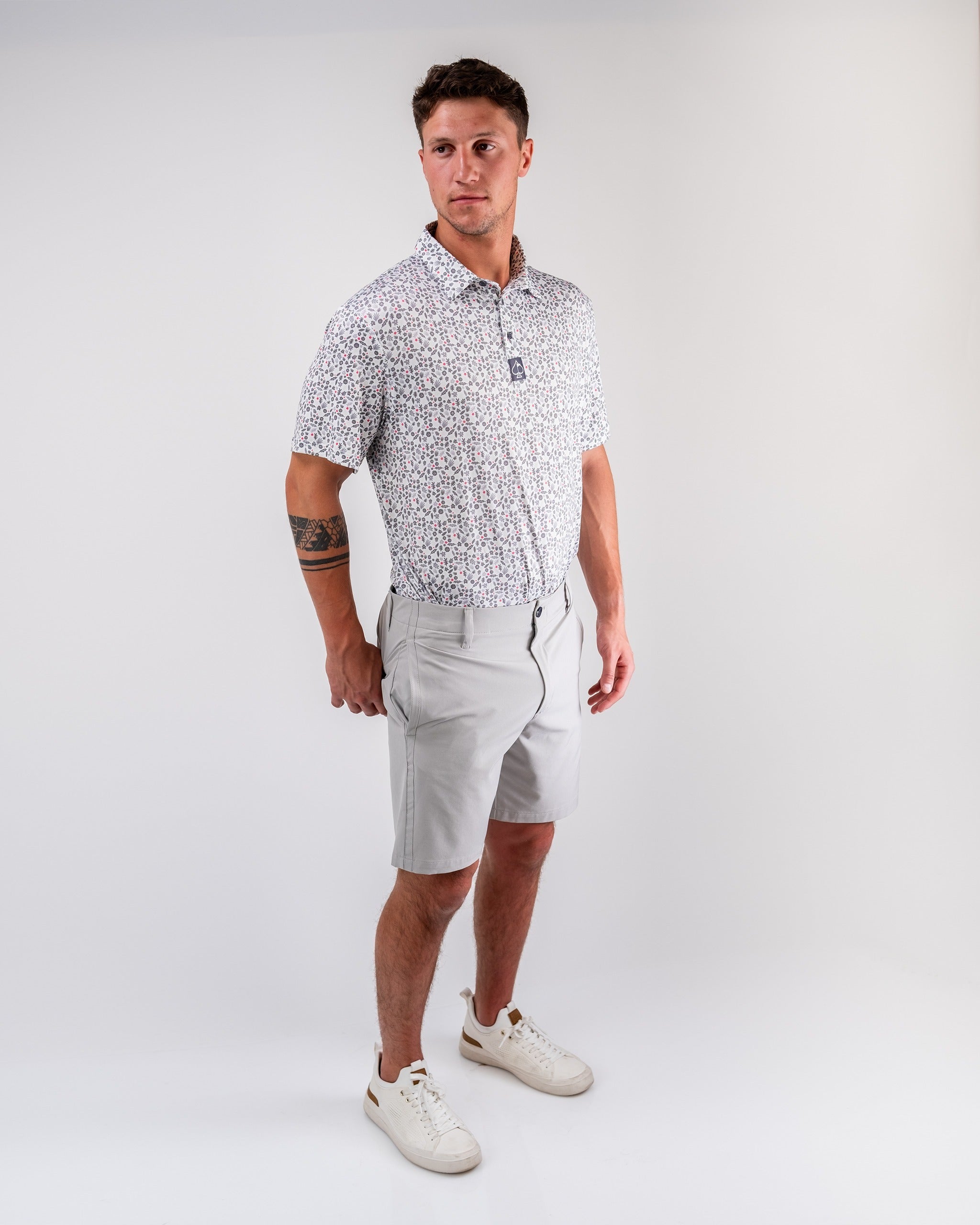 Men's performance shorts in dark stone, paired with a patterned shirt, ideal for stylish golfing on the course.