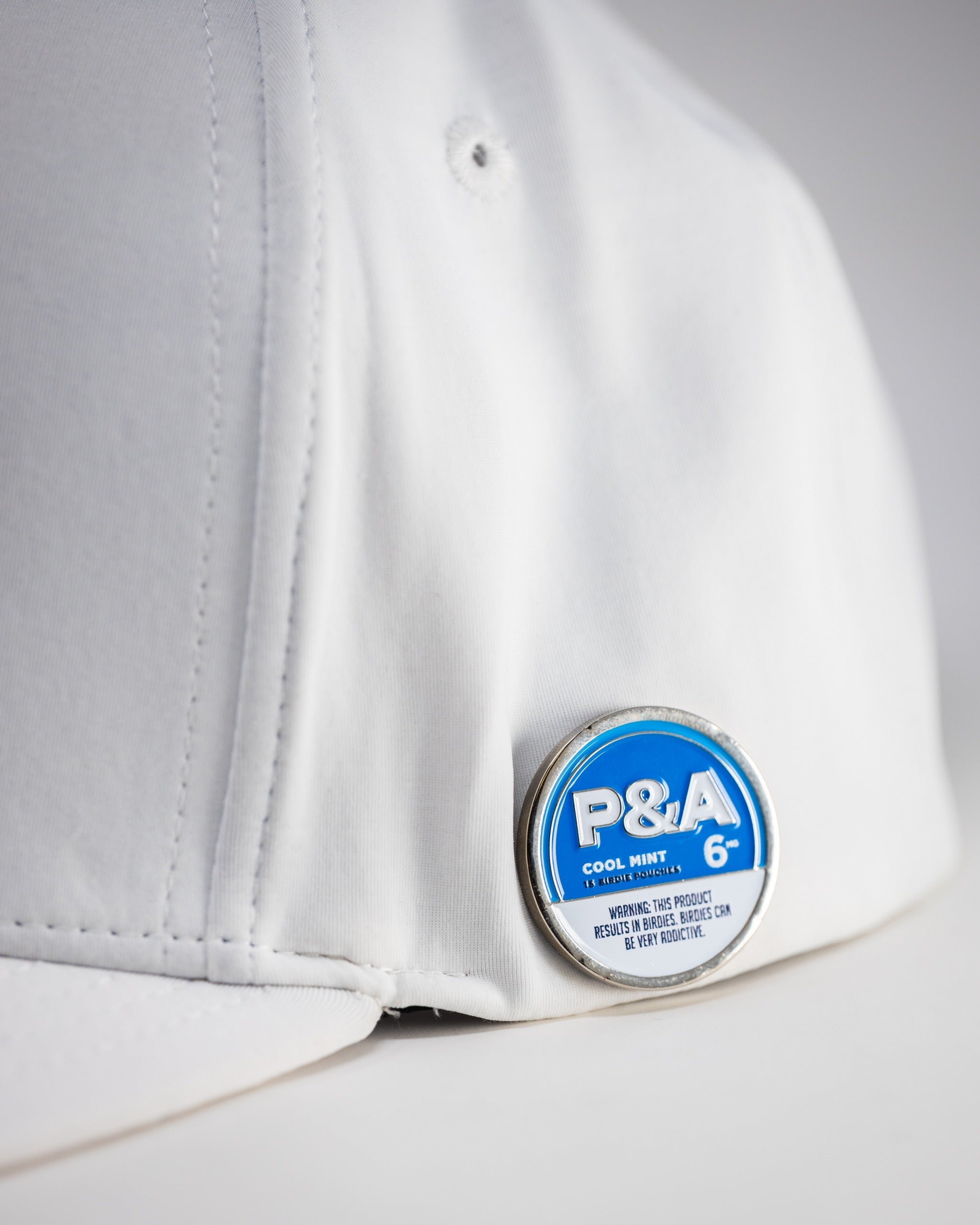 White Performance Spade Hat featuring a blue P&A logo on the side, designed for stylish golfers seeking comfort.