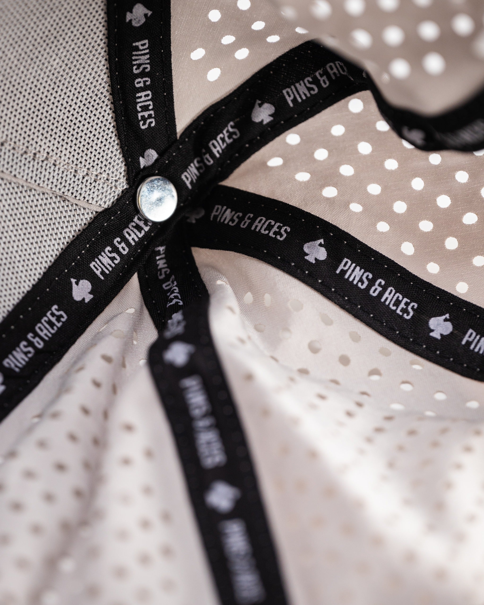 Interior view of a perforated bone-colored rope hat featuring a black Pins & Aces label and breathable design.