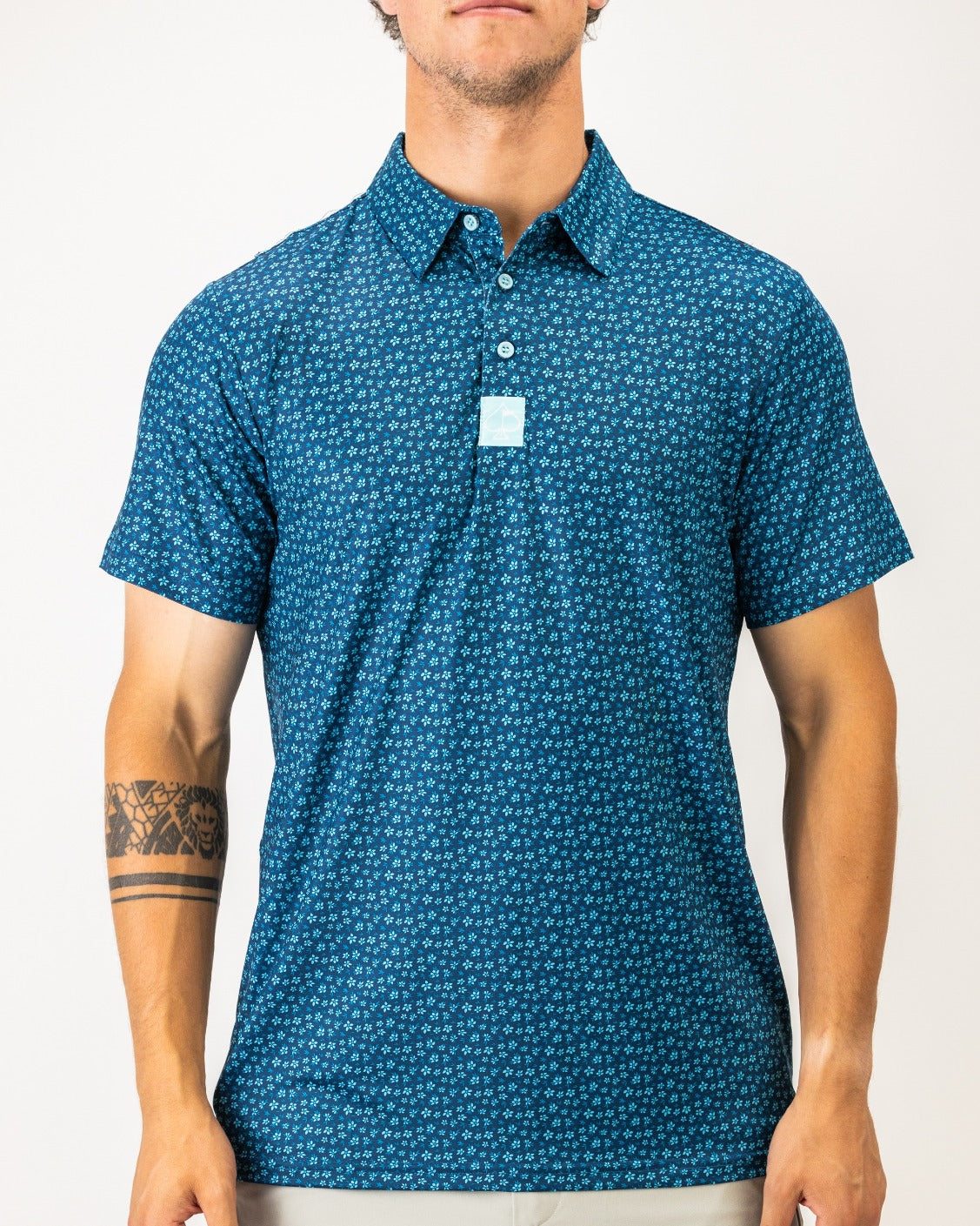 Men's short-sleeve golf shirt in blue with a micro floral pattern, featuring a button-down collar and a chest logo.
