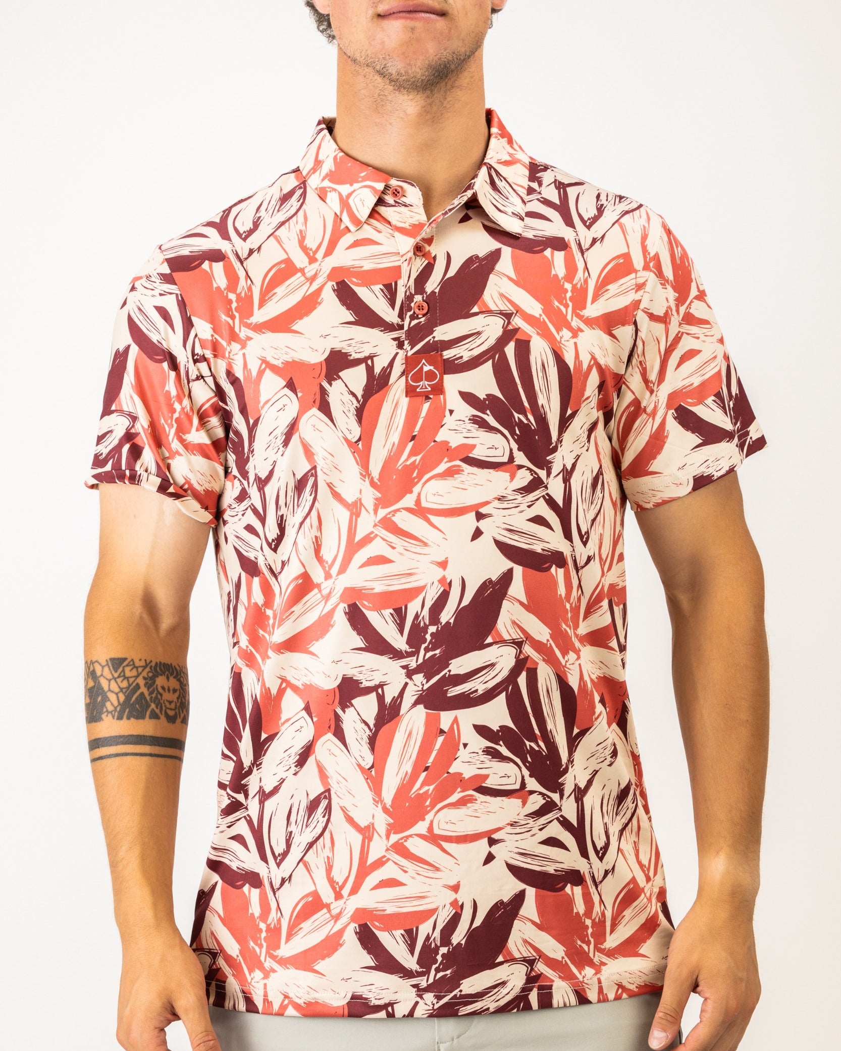 Men's brushed floral golf polo featuring a vibrant leaf pattern in red and cream tones, perfect for stylish play on the course.