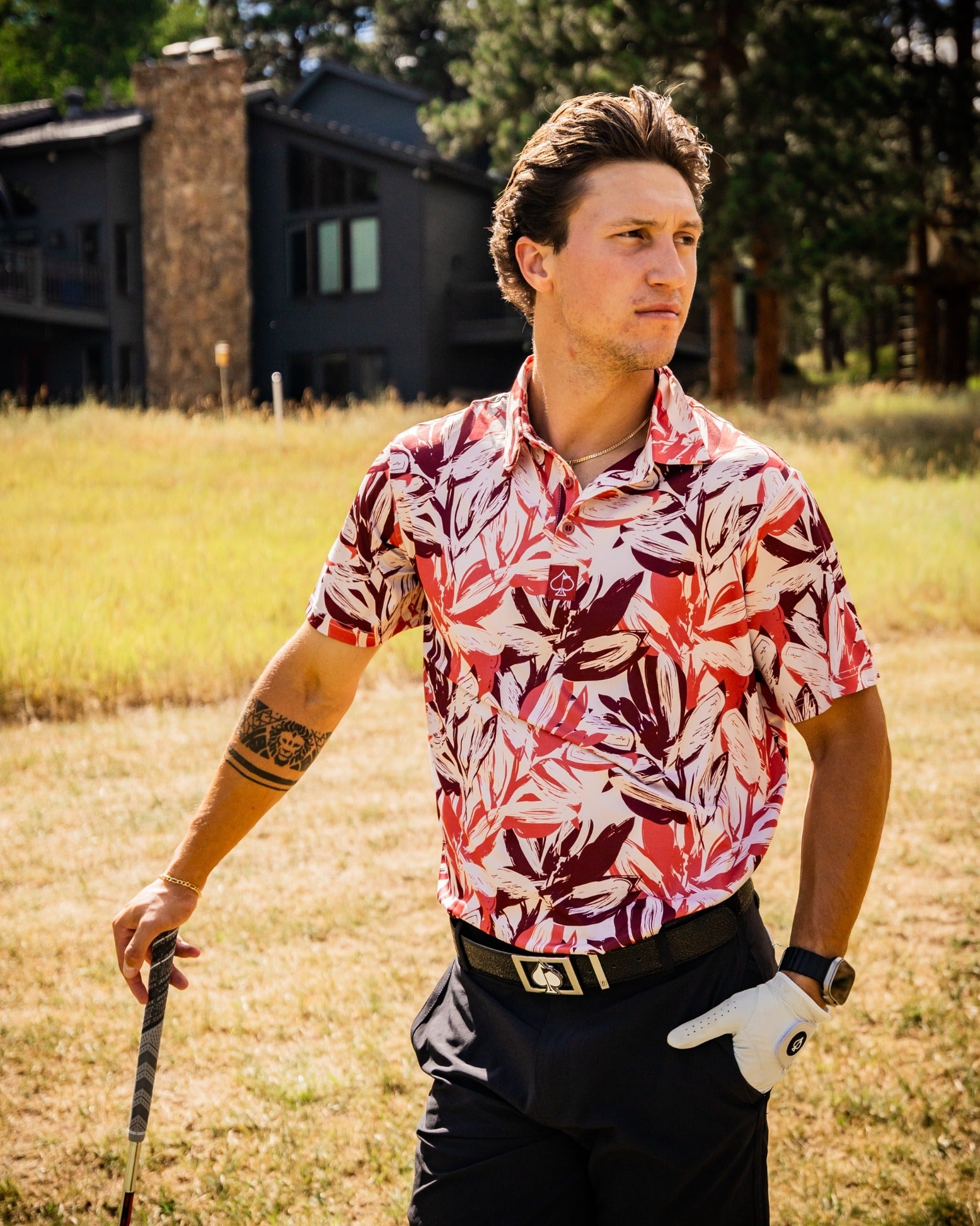 Stylish golfer wearing a brushed floral polo shirt, posing confidently on a sunny course with a scenic background.
