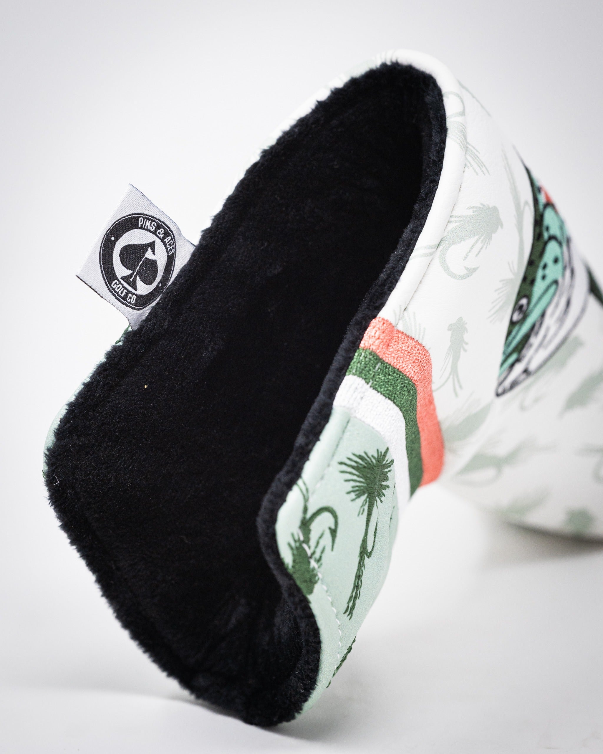 Trout Blade Putter Cover featuring a vibrant design with fish and palm trees, lined with soft black fabric for protection.