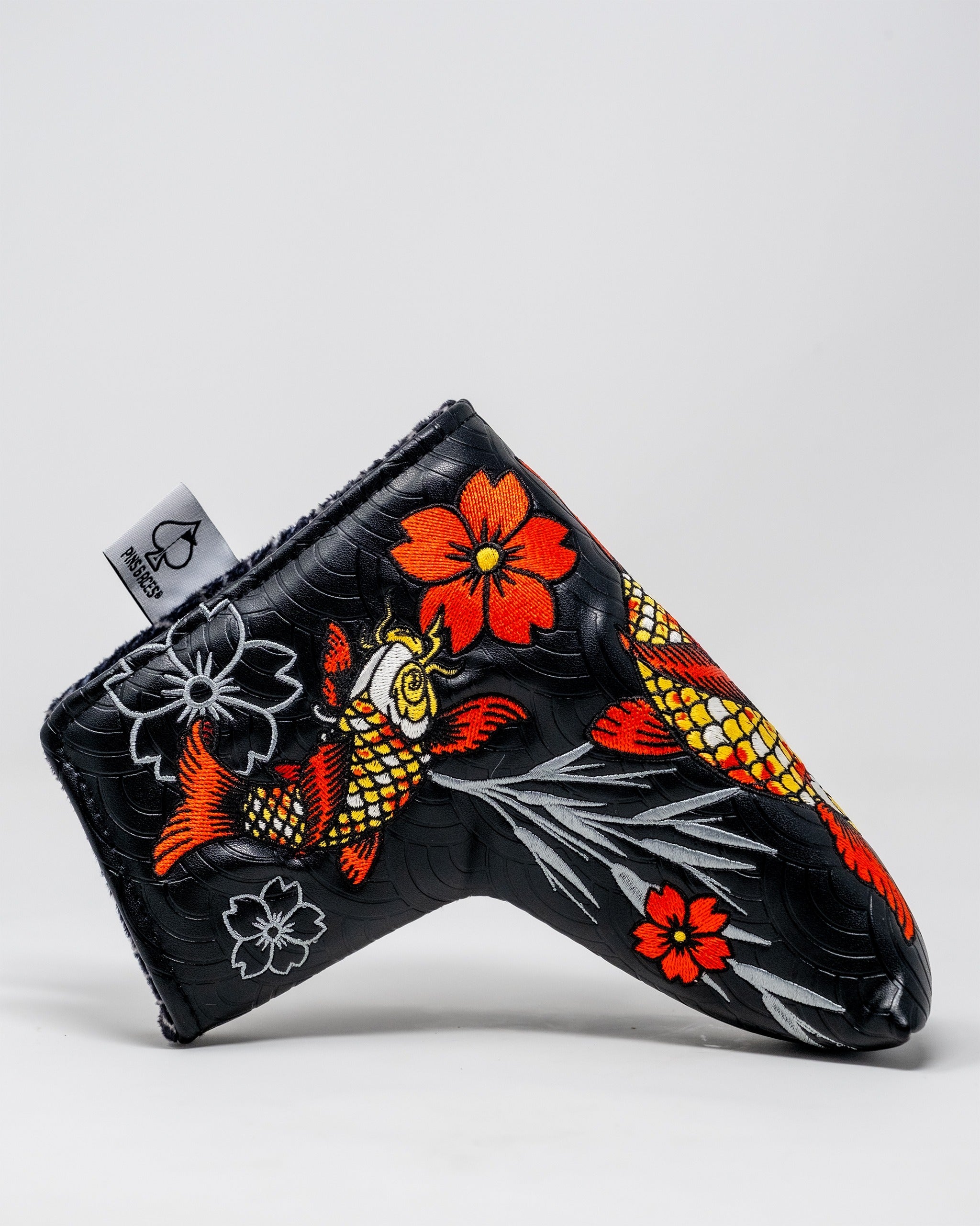 Bold Koi Flow blade putter cover featuring vibrant koi fish and floral designs on a sleek black background.