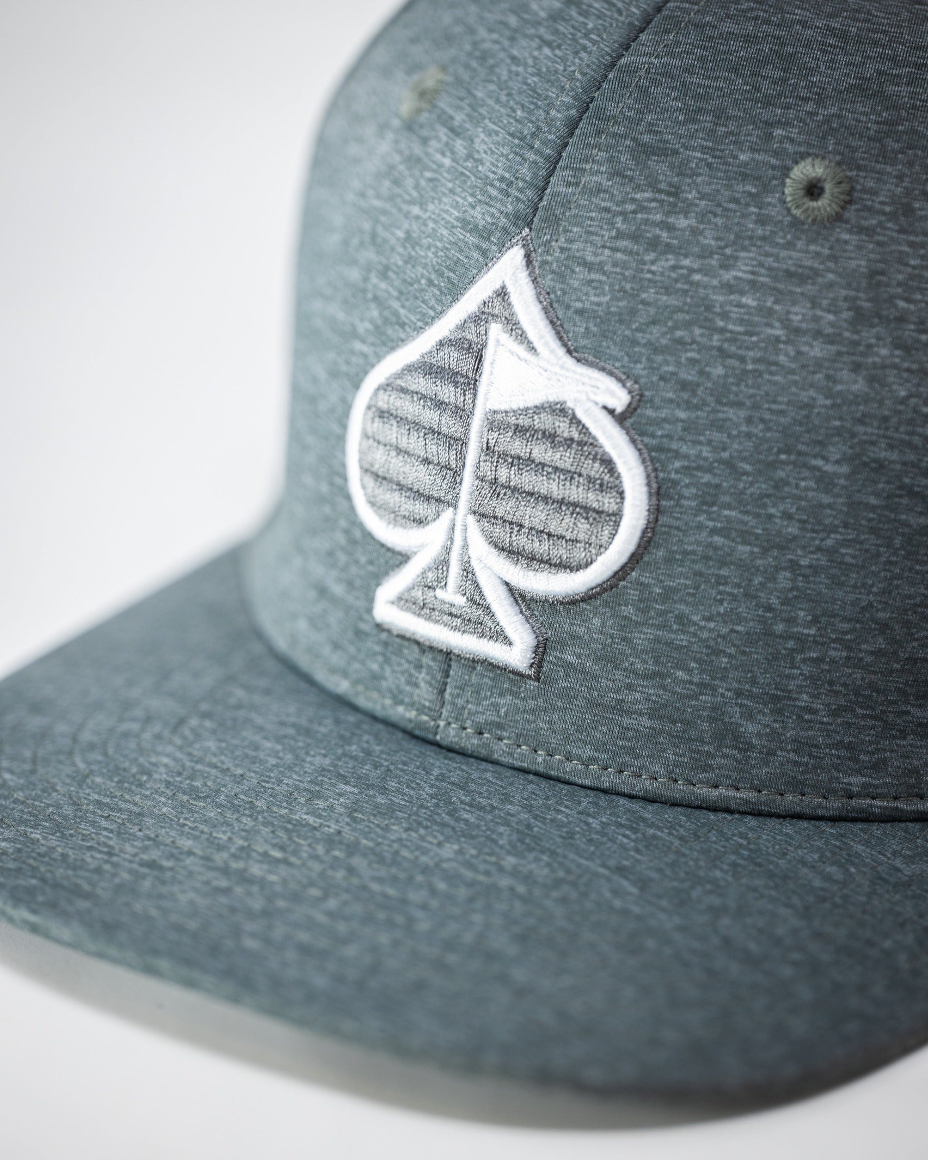 Ash performance hat featuring a textured spade logo, designed for golfers seeking style and comfort on the course.