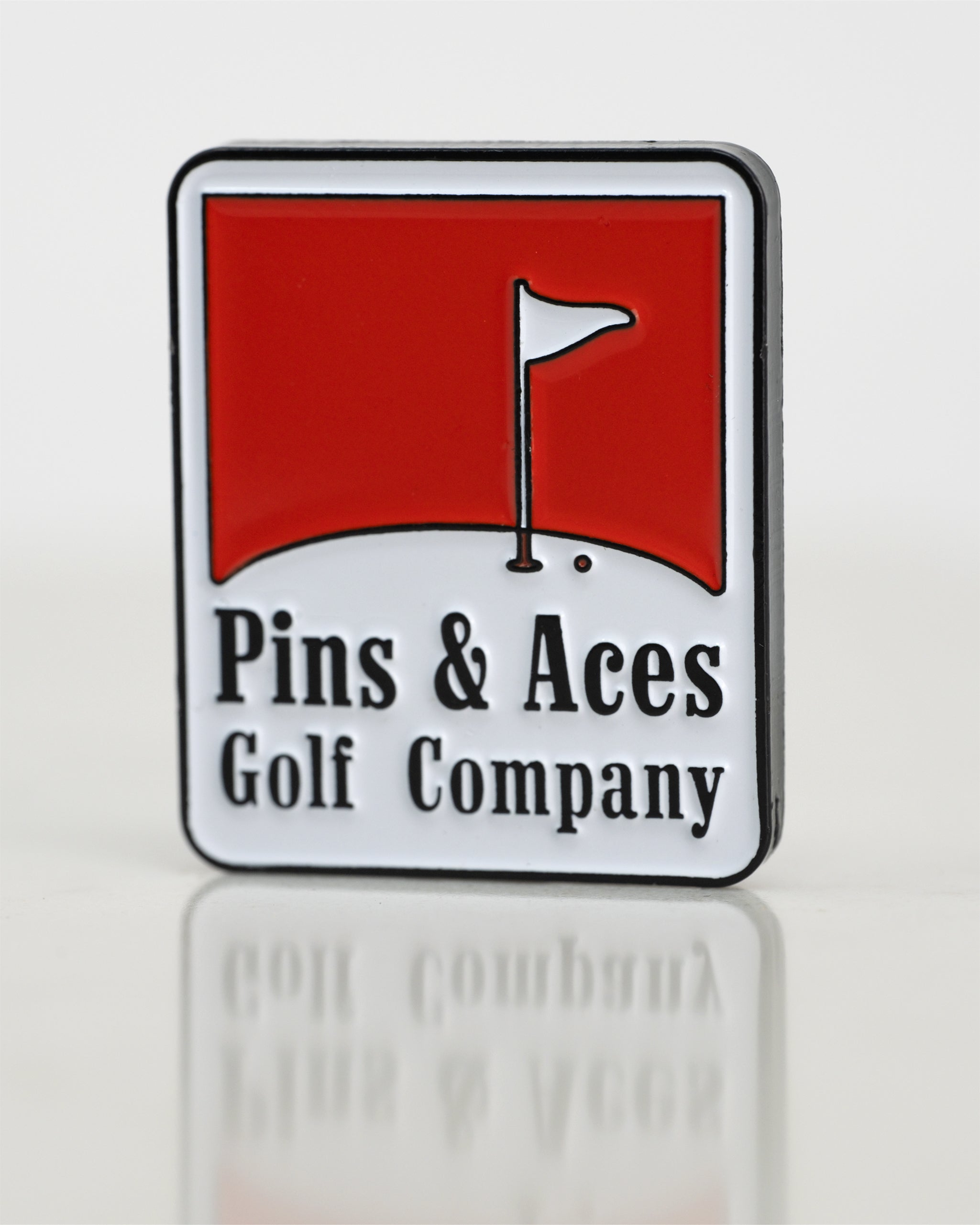 Bold red Pins & Aces ball marker featuring a golf flag design, perfect for stylish golfers on the course.