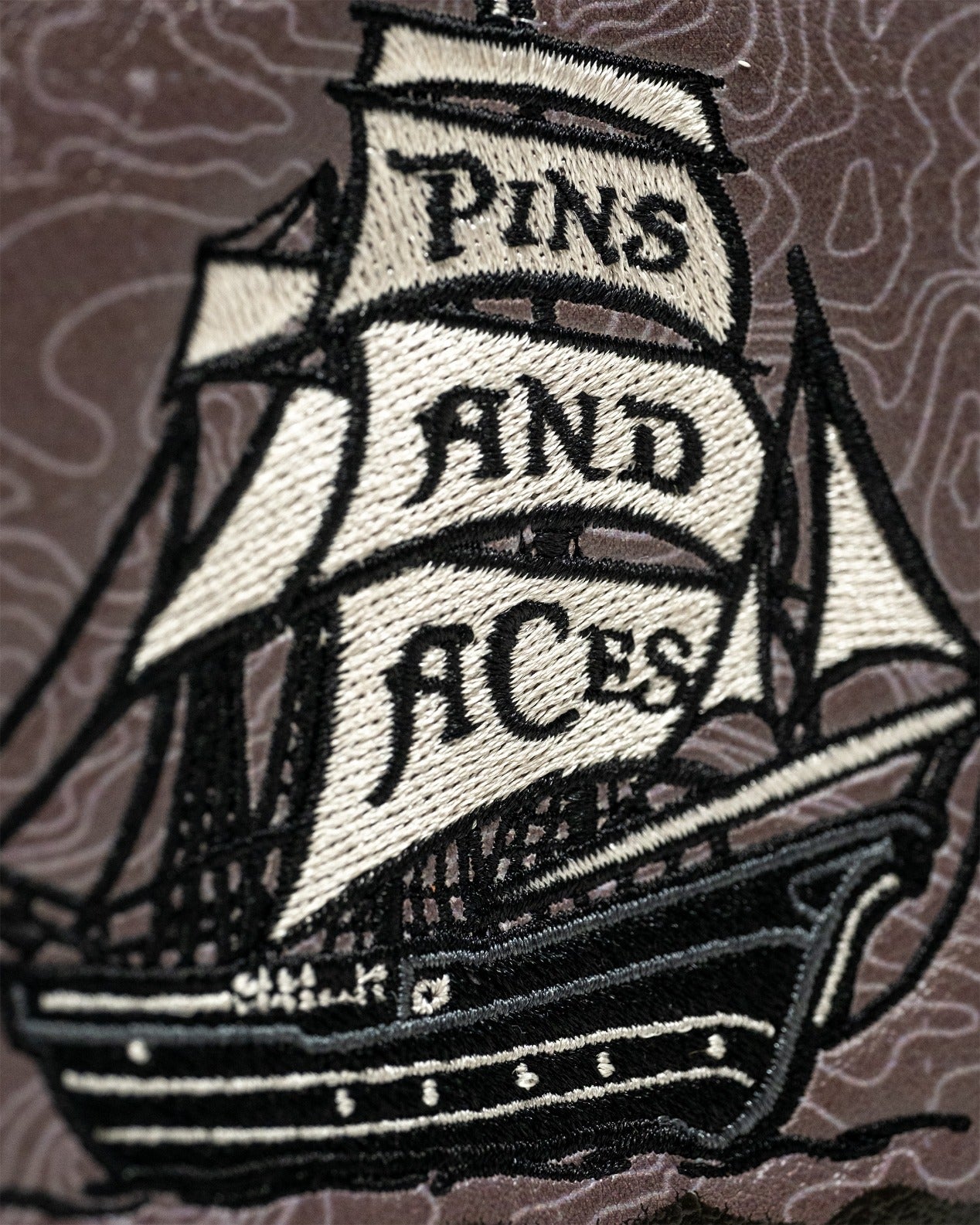 Pirate-themed mallet putter cover featuring an embroidered ship with "Pins and Aces" on a textured background.