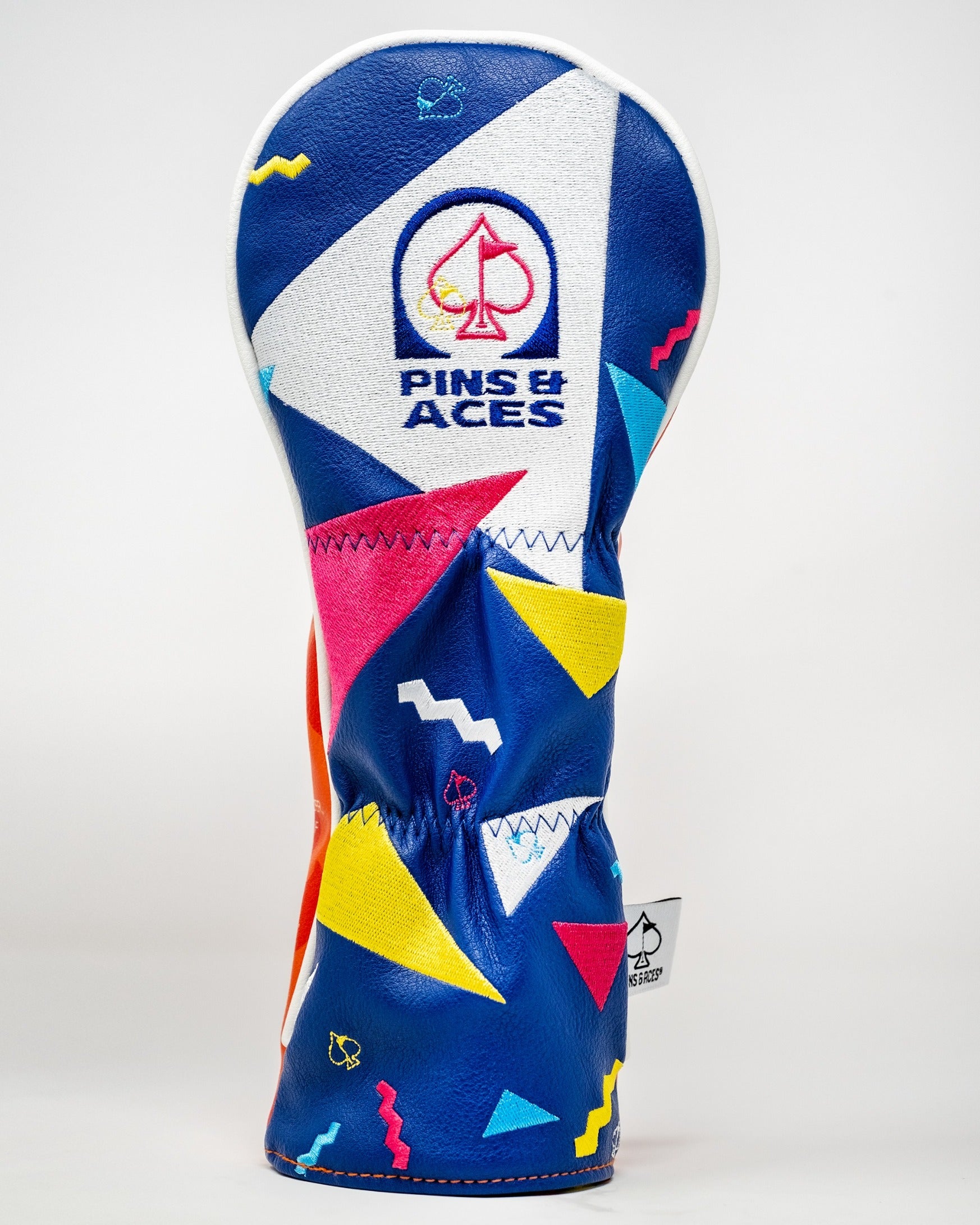 Bold golf headcover featuring a vibrant geometric design in blue, red, and yellow, branded with Pins and Aces logo.