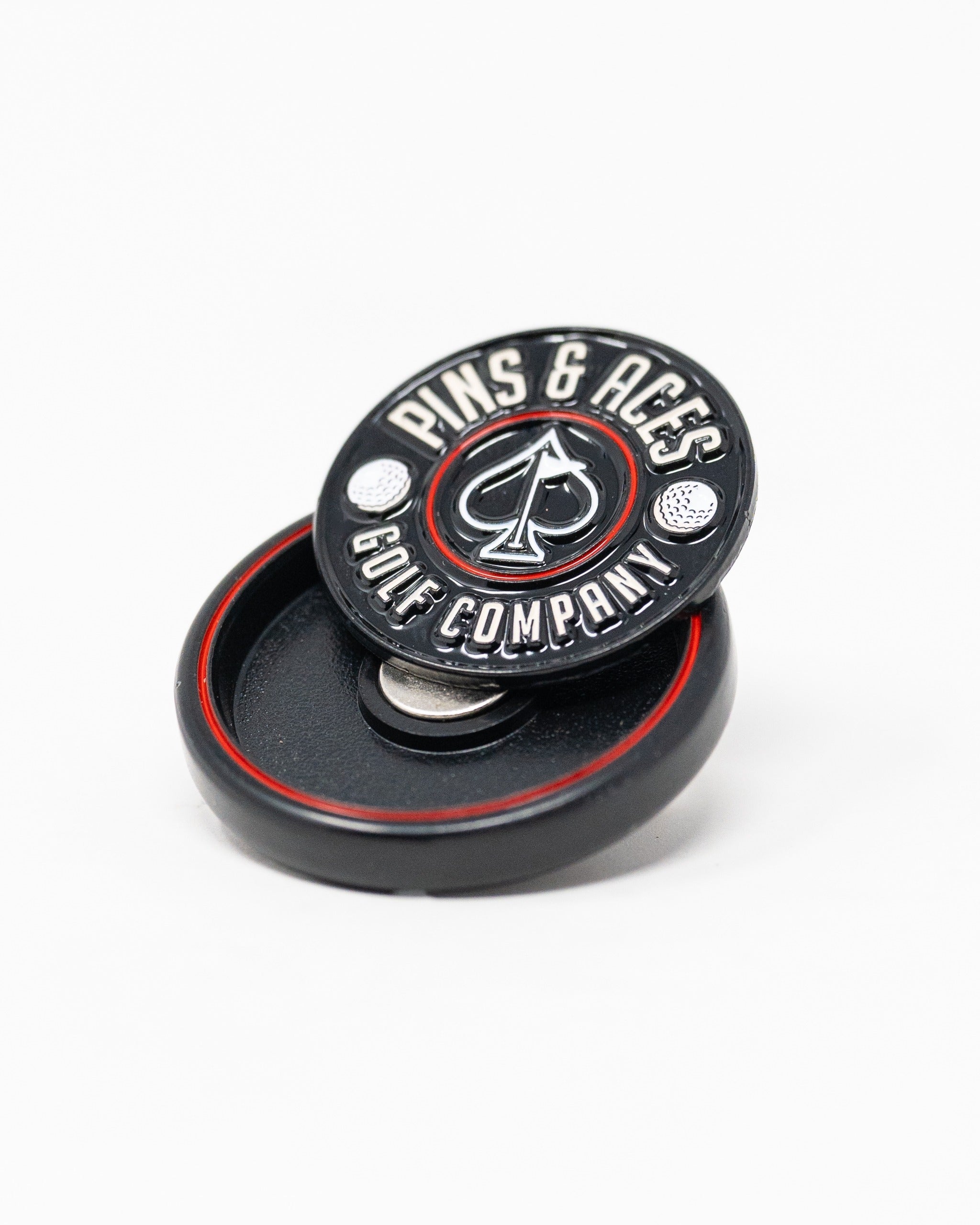 Black pop-out medallion ball marker featuring the Pins and Aces logo, ideal for stylish golfers on the course.
