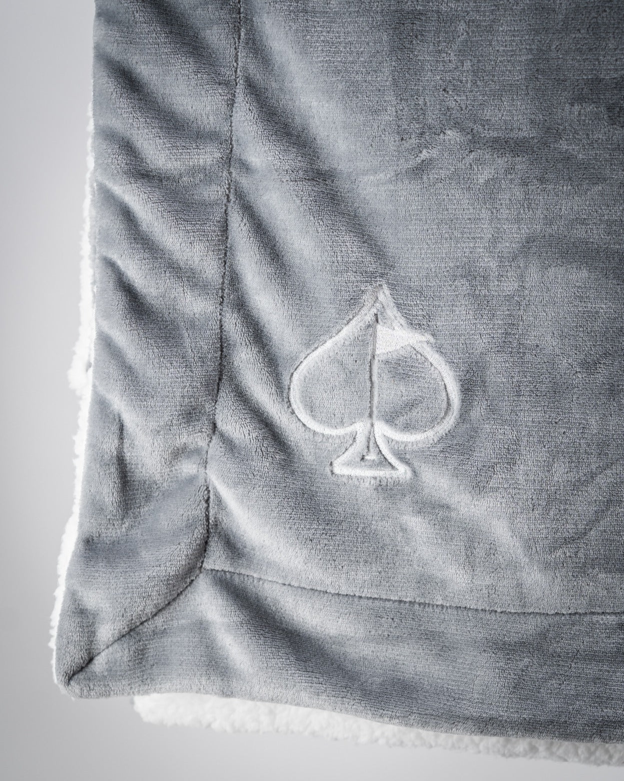 Light gray Bogey Blanket featuring a soft texture and an embroidered spade logo, perfect for cozying up after a round of golf.