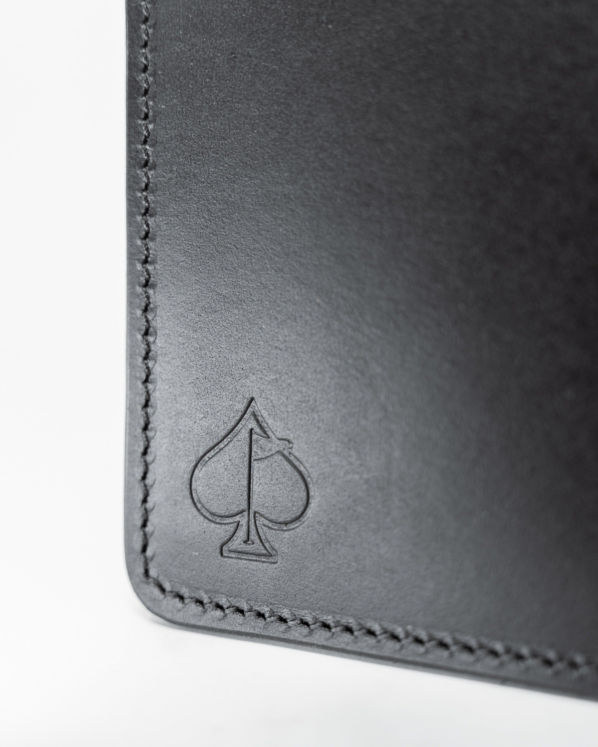 Smooth Italian black leather wallet featuring a subtle embossed spade logo, showcasing elegant craftsmanship.