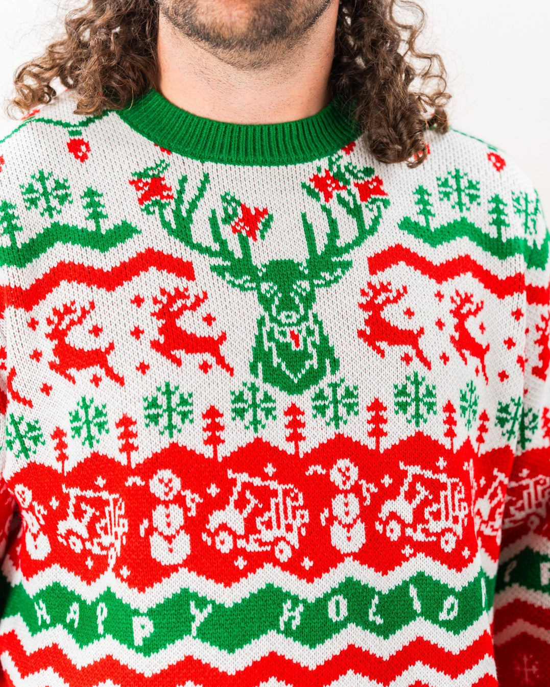 A man wearing a festive red and green ugly sweater featuring reindeer, snowflakes, and holiday motifs for 2024.