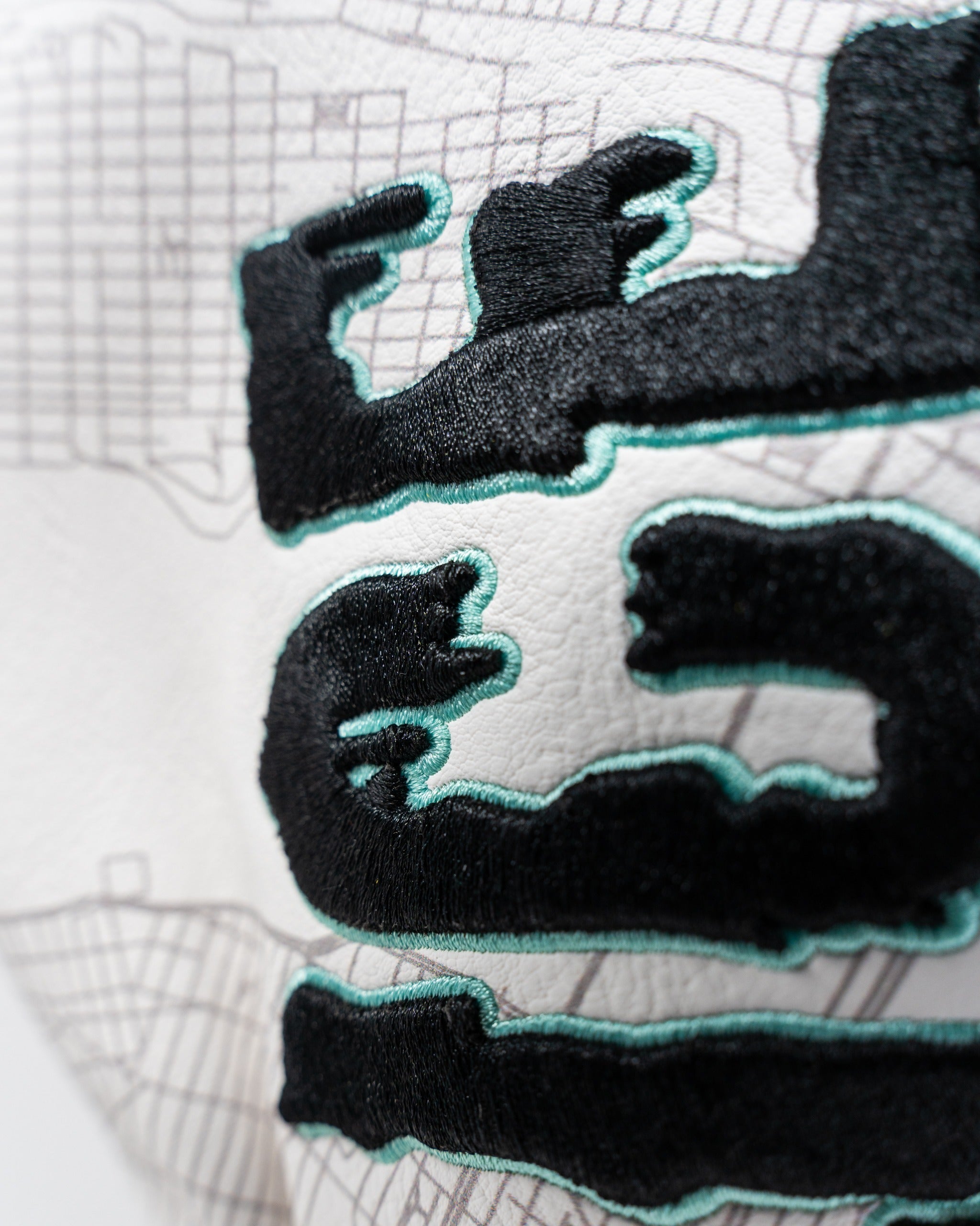 Close-up of the Shady Slice Fairway Cover featuring bold black embroidery on a textured white background.