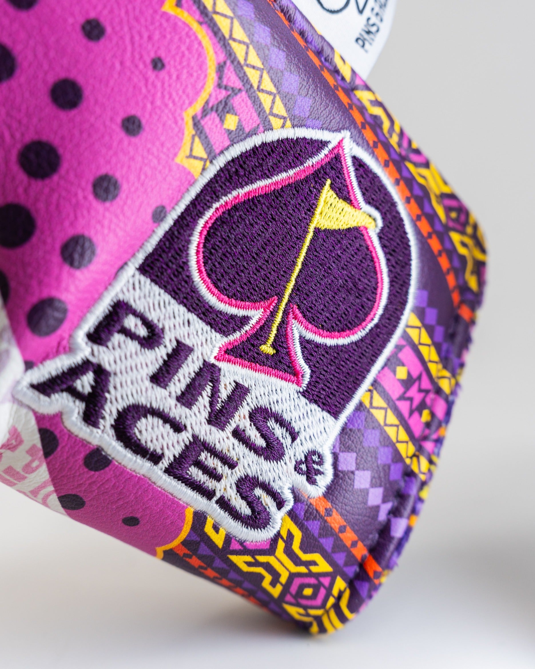 Bold purple and pink blade putter cover featuring a unique design and the Pins and Aces logo for standout style on the course.