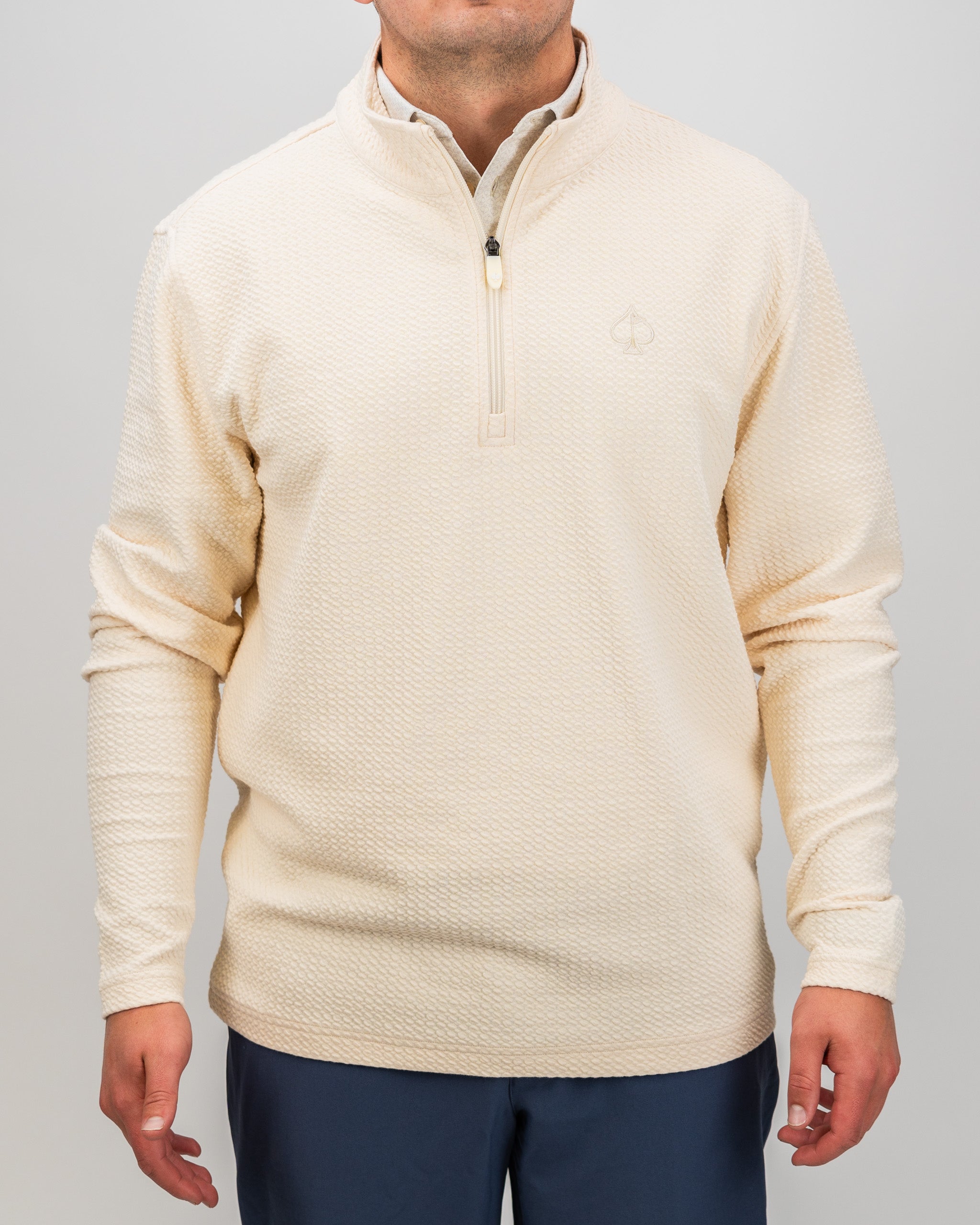 Cream waffle knit pullover with a quarter zip and subtle logo, designed for comfort and style on the golf course.