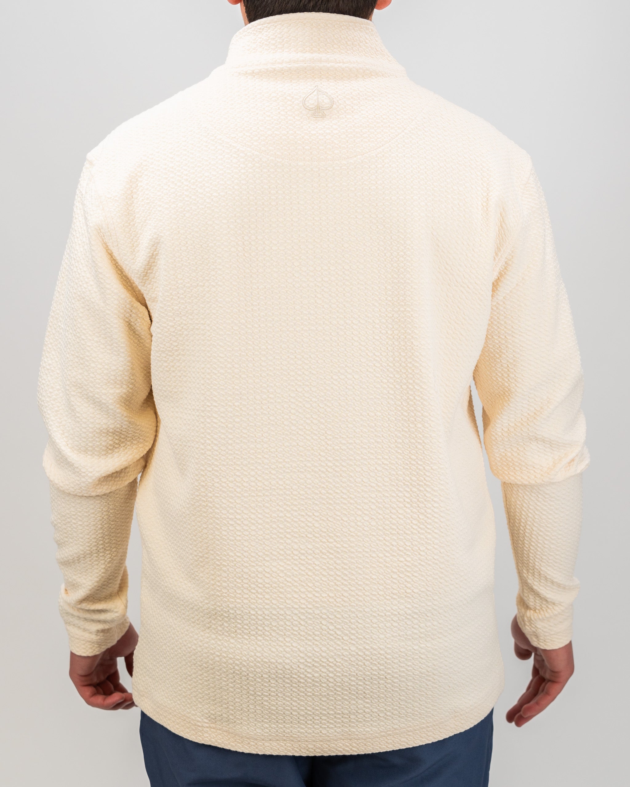 Cream waffle knit pullover with a relaxed fit, featuring a high collar and long sleeves, ideal for stylish golf outings.