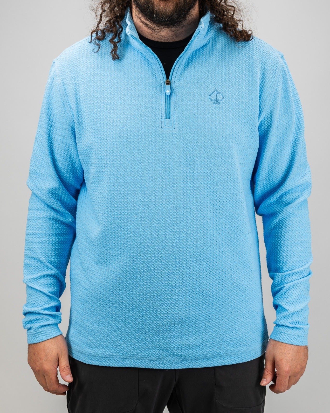 Light blue waffle knit pullover with a quarter zip and logo, designed for comfort and style on the golf course.