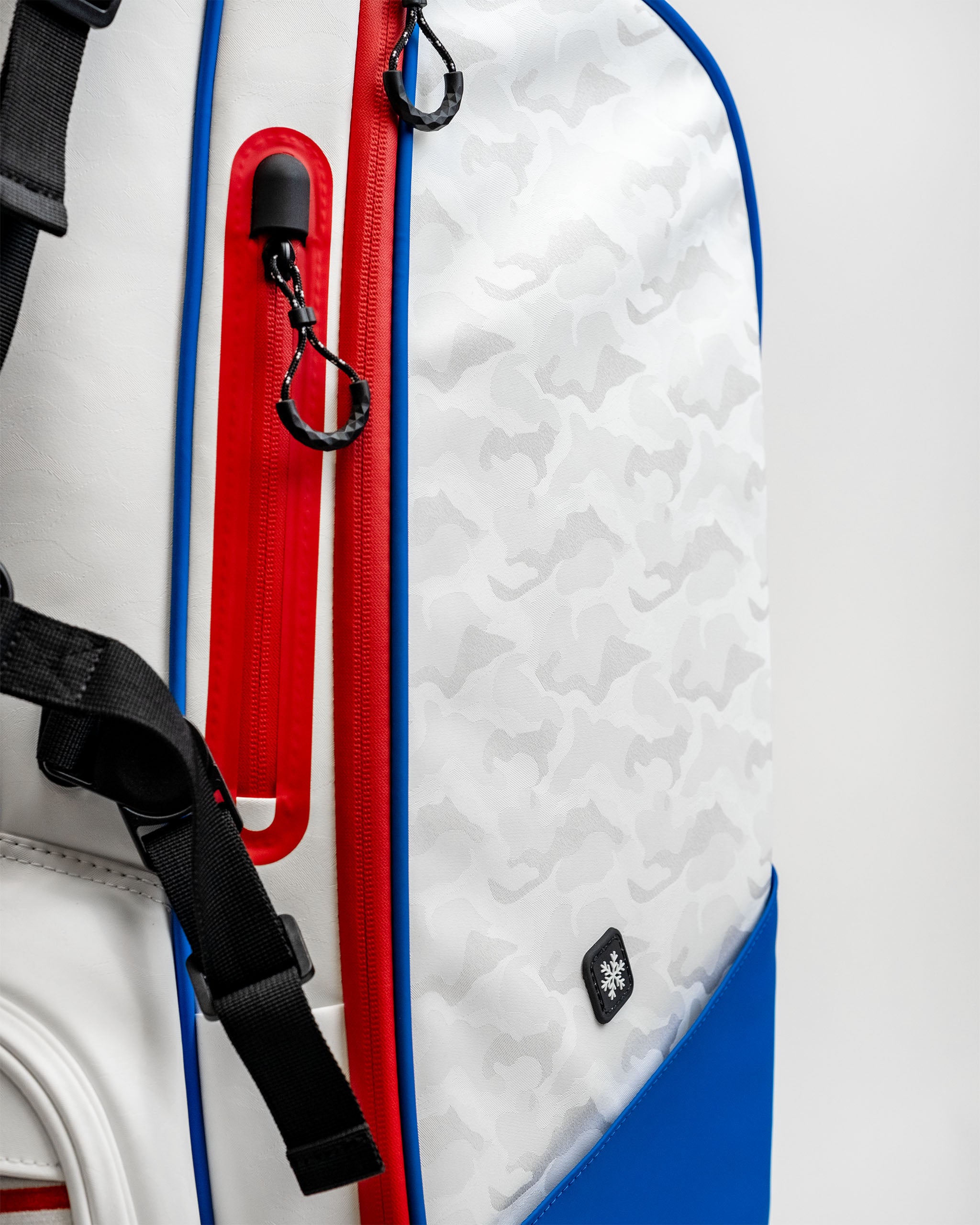 Close-up of the Player Preferred Golf Bag featuring a white camo pattern with red and blue accents and zippers.