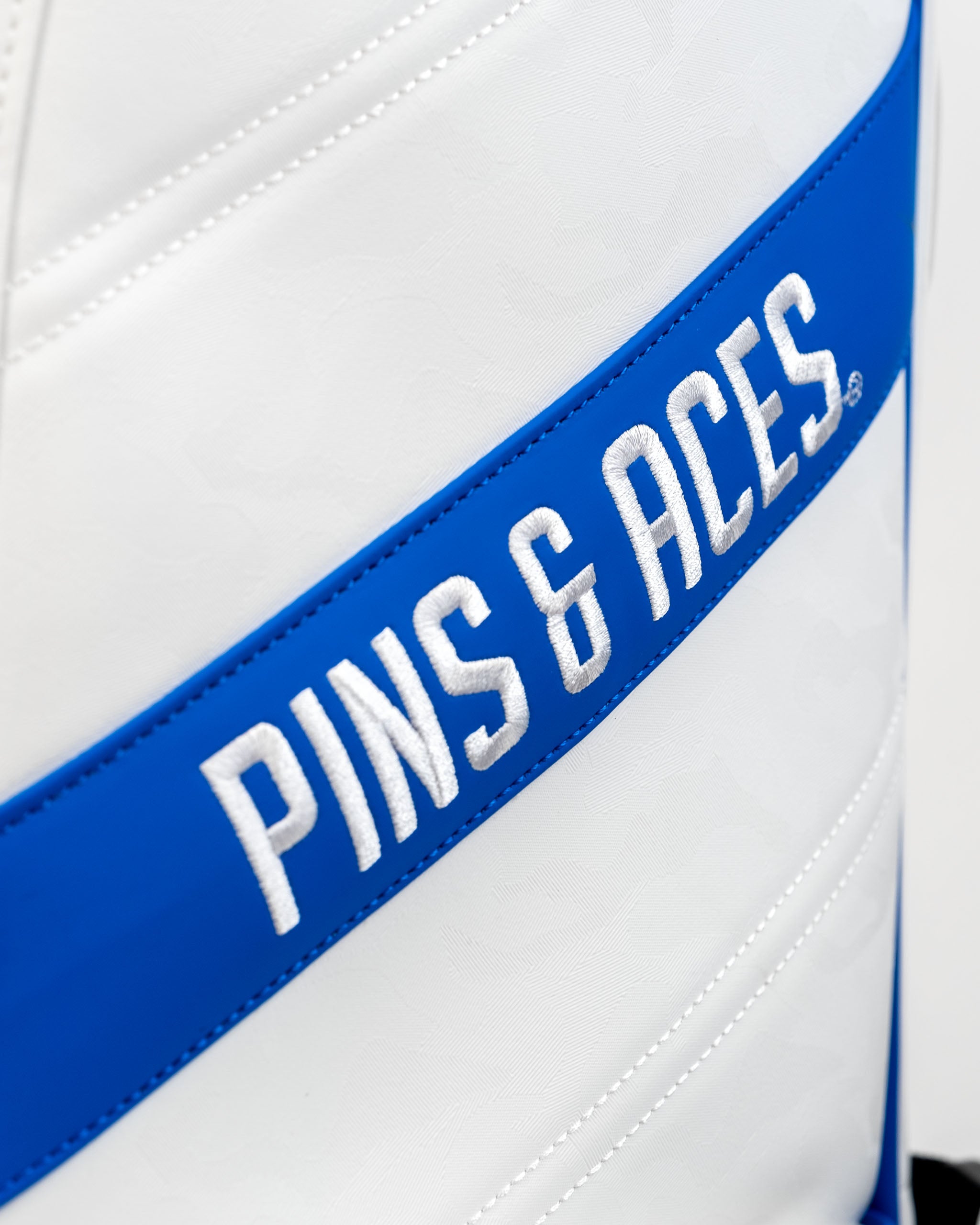 Player Preferred Golf Bag in white with bold blue accents featuring the Pins and Aces logo prominently displayed.
