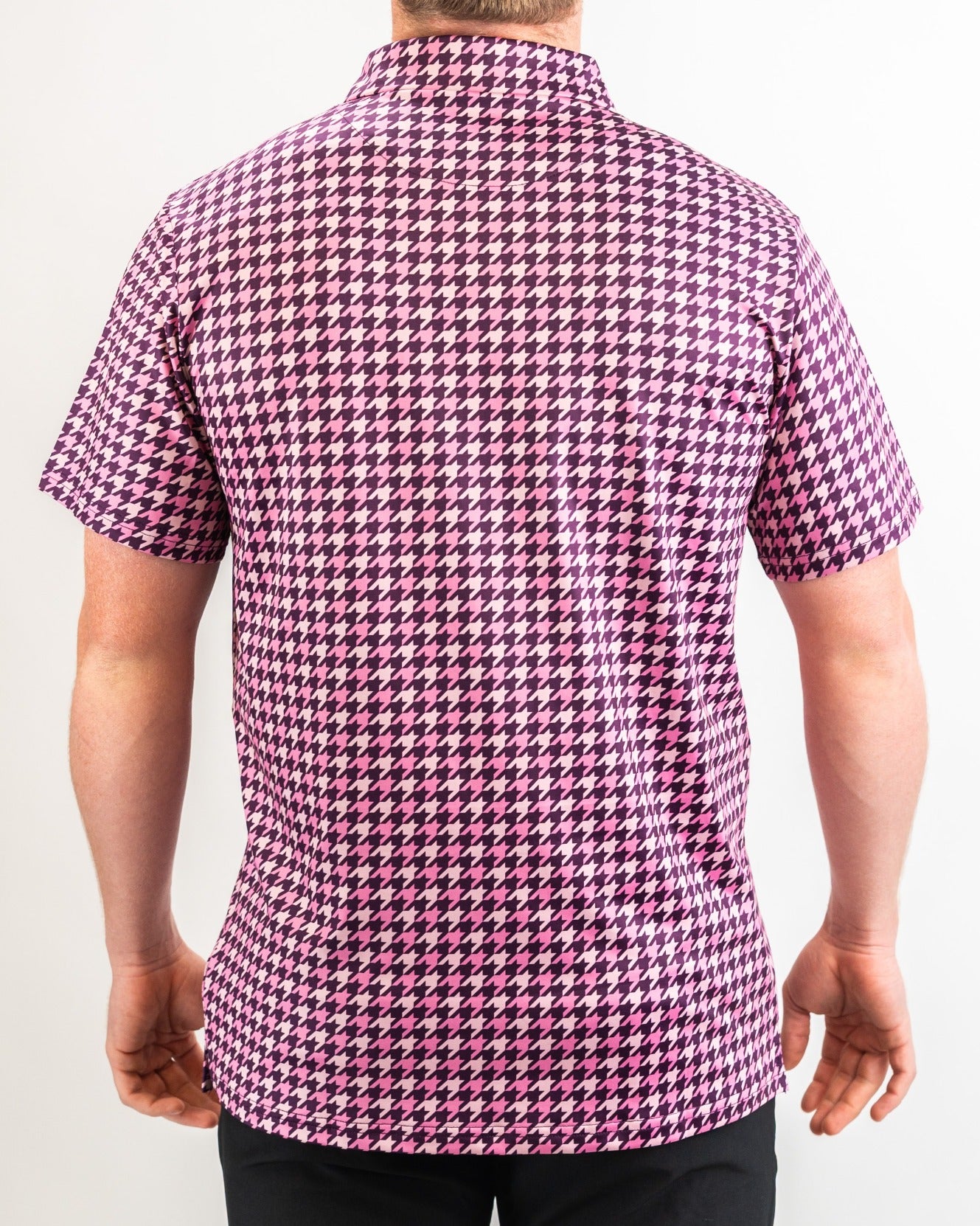 Men's short-sleeve golf shirt featuring a bold houndstooth pattern in raspberry and pink tones, viewed from the back.