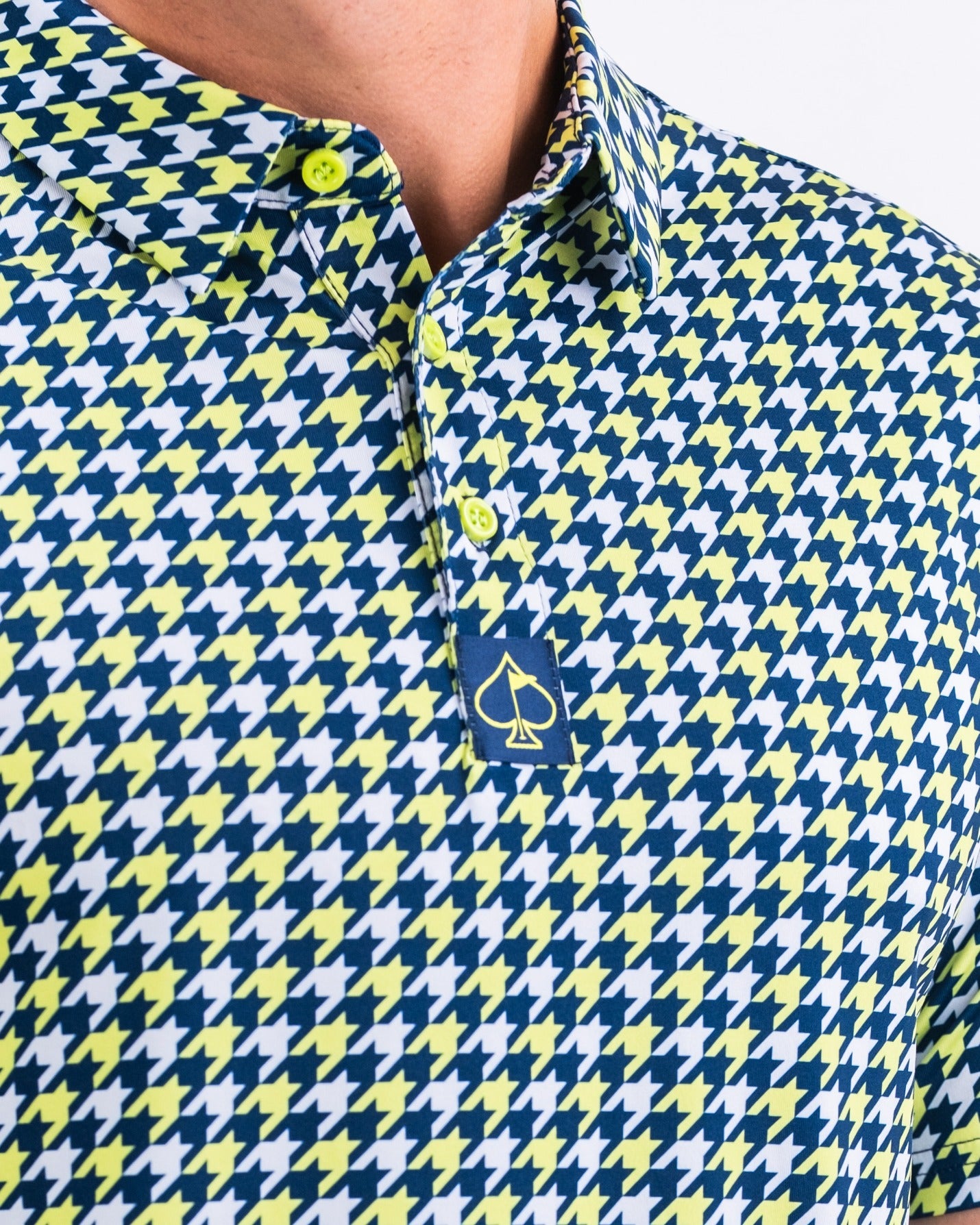 Lime houndstooth golf polo featuring a bold pattern, vibrant colors, and a stylish logo on the collar.