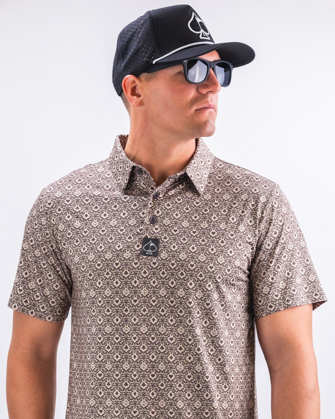 Stylish golfer wearing the Big Blind Ash polo, paired with a black cap and sunglasses, showcasing bold golf fashion.