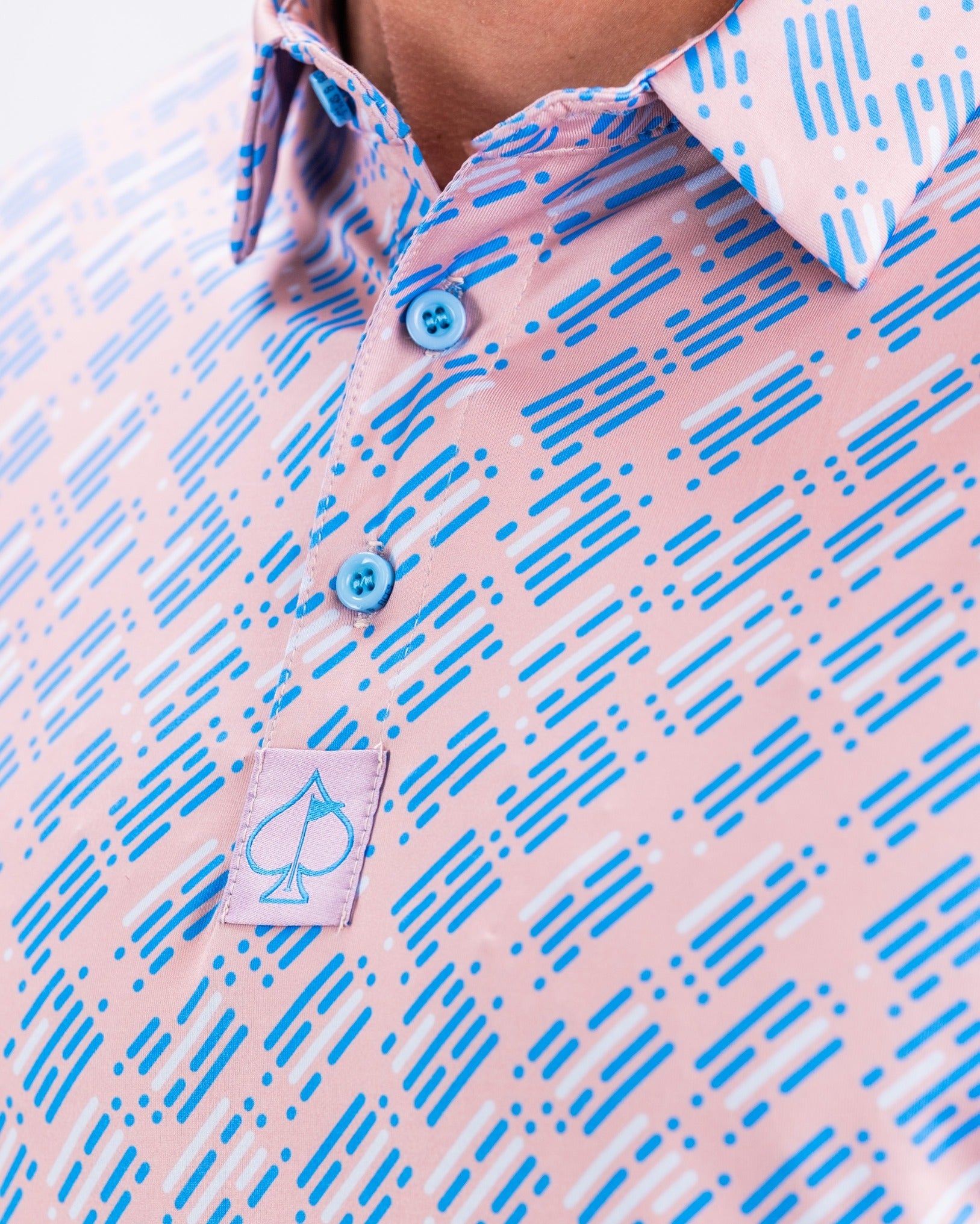 Close-up of the Skyline Dash Pink golf shirt featuring a vibrant pattern of blue and white lines on a pink background.