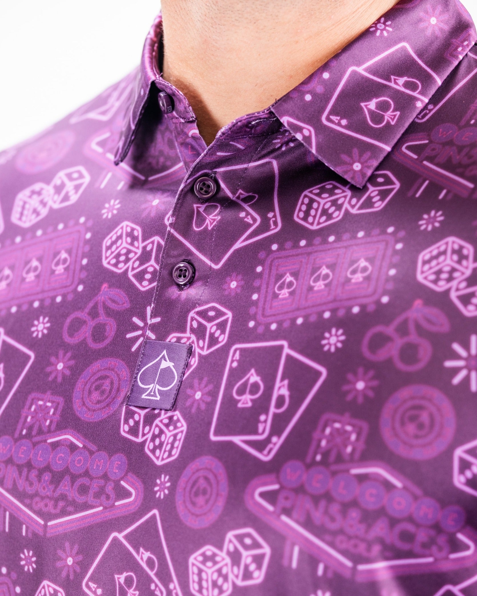 Bold purple golf polo featuring a playful pattern of playing cards, dice, and golf-themed icons for a standout look.