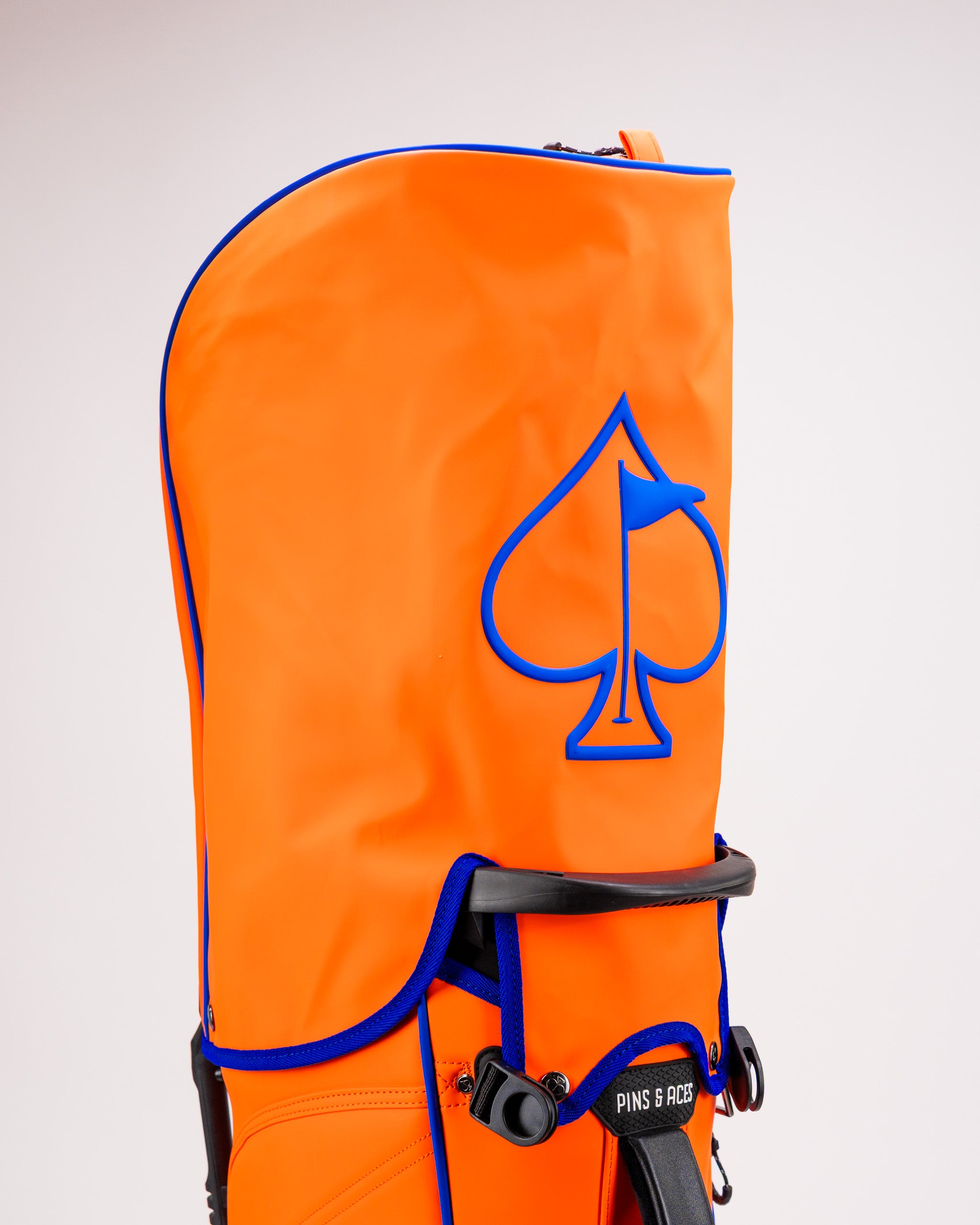 Vibrant orange golf bag featuring a blue spade logo, designed for style and functionality on the course.