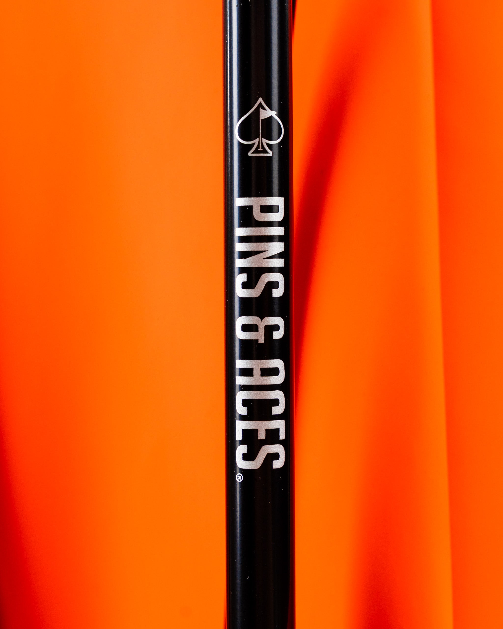Player Preferred Golf Bag in vibrant orange with a sleek black handle featuring the Pins and Aces logo.