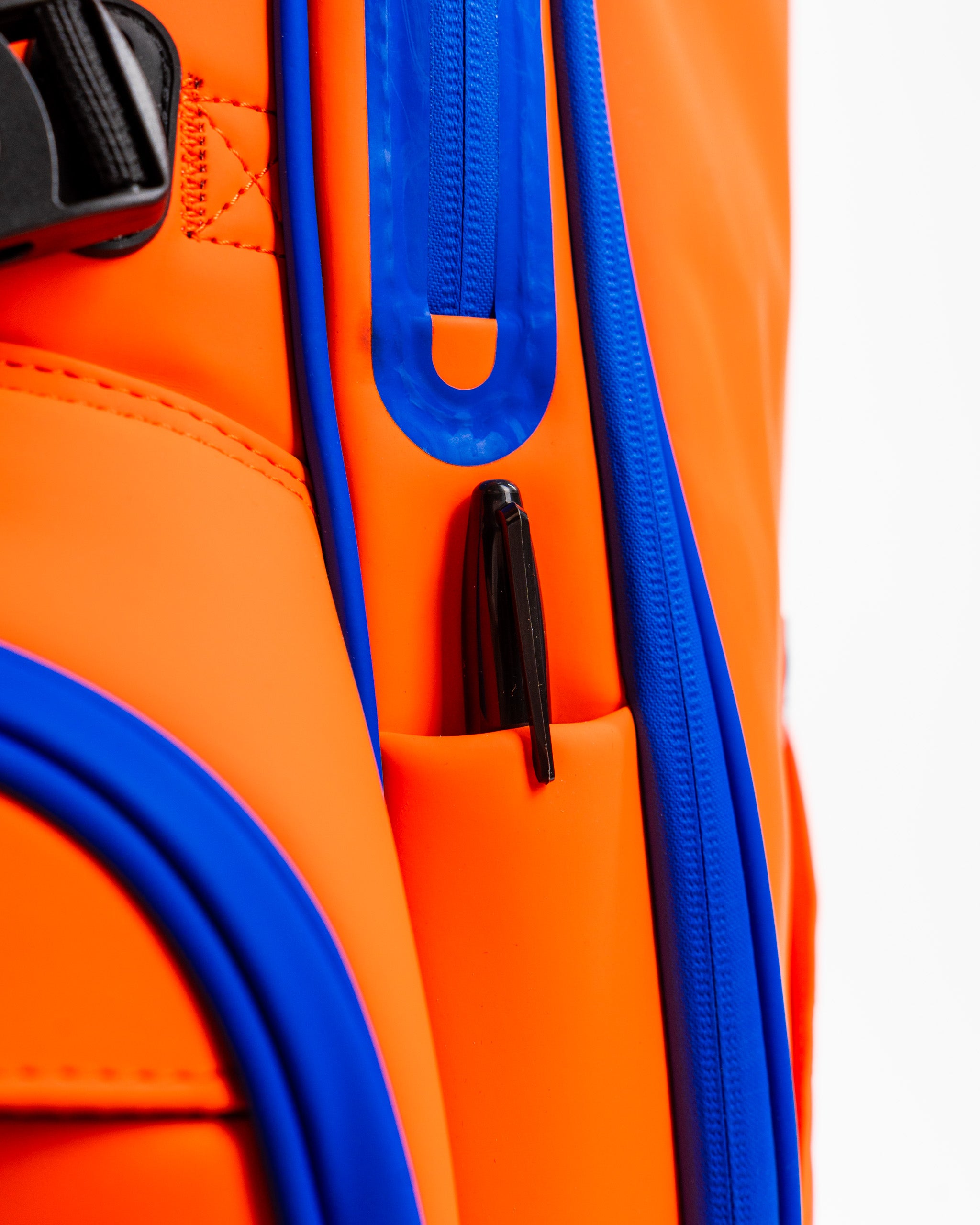 Close-up of the Player Preferred Golf Bag in vibrant orange with blue accents, featuring a pen holder and zipper detail.