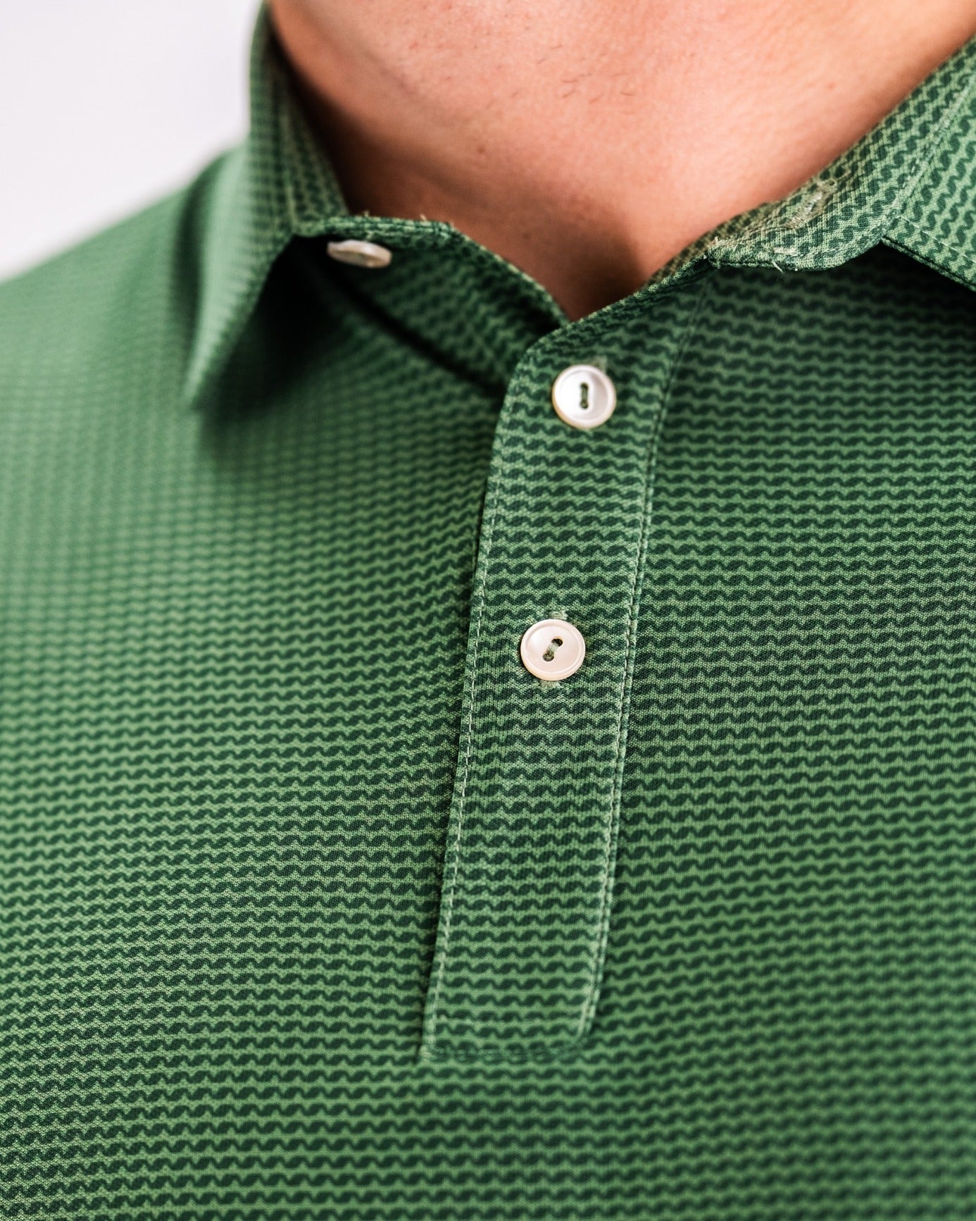 Close-up of a green Player Preferred Polo featuring a textured pattern and a classic collar with button details.