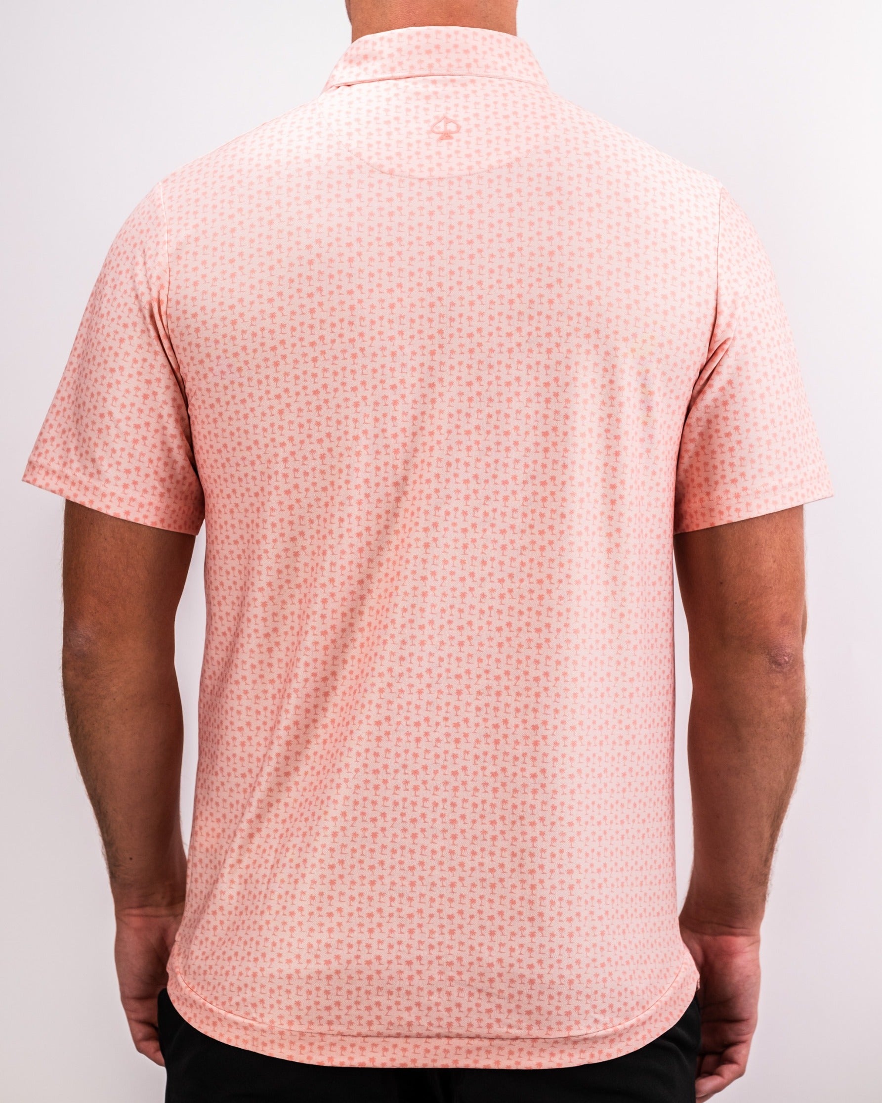 Men's coral polo shirt featuring a palm pattern, designed for comfort and style on the golf course.